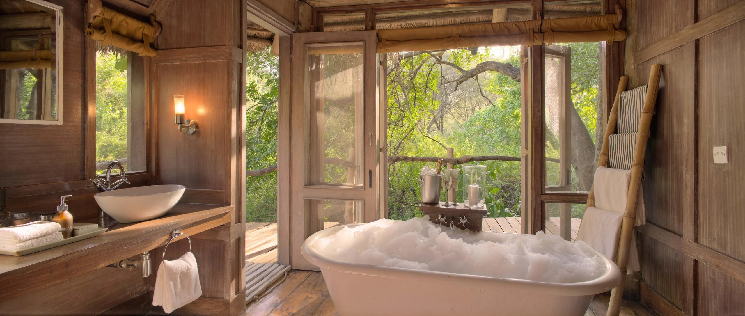 A bathroom with a freestanding bath and forest views