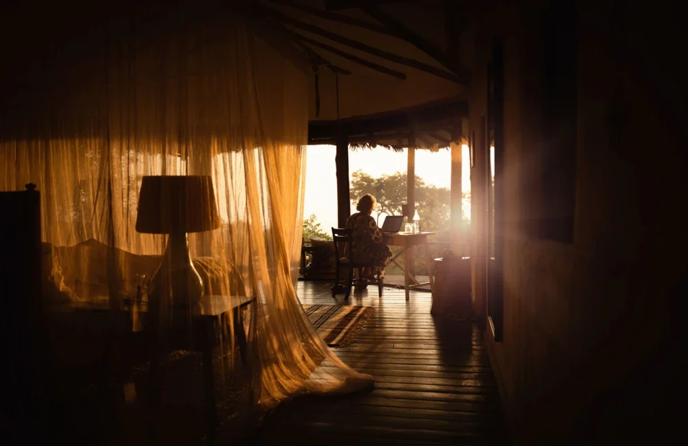 A bedroom at sunrise with the view beyond the drapes