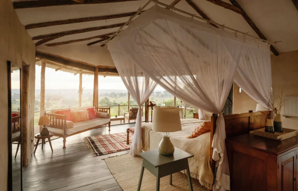 A bedroom with a canopied bed and the plains beyond