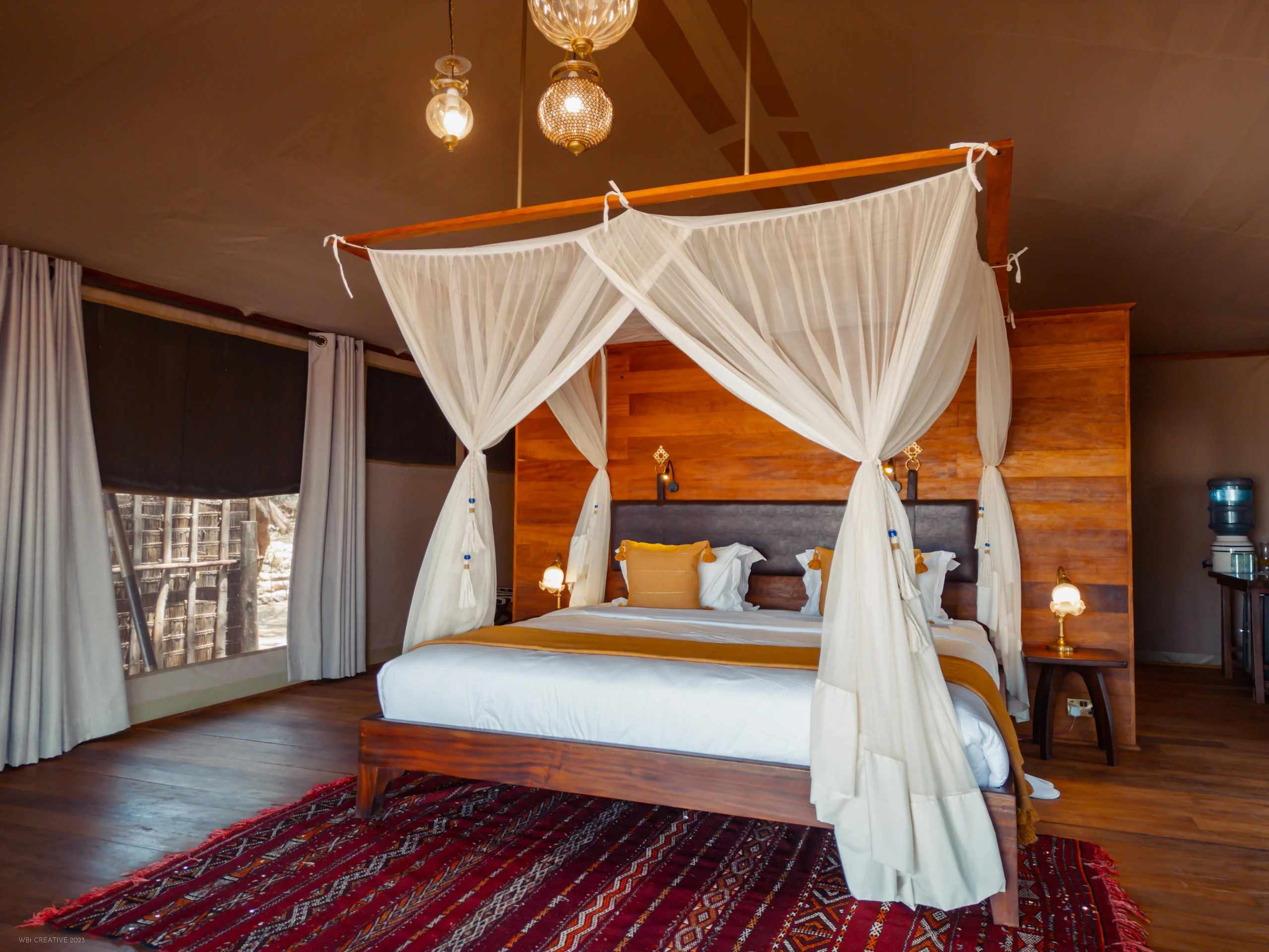 A tent bedroom with a draped four-poster bed
