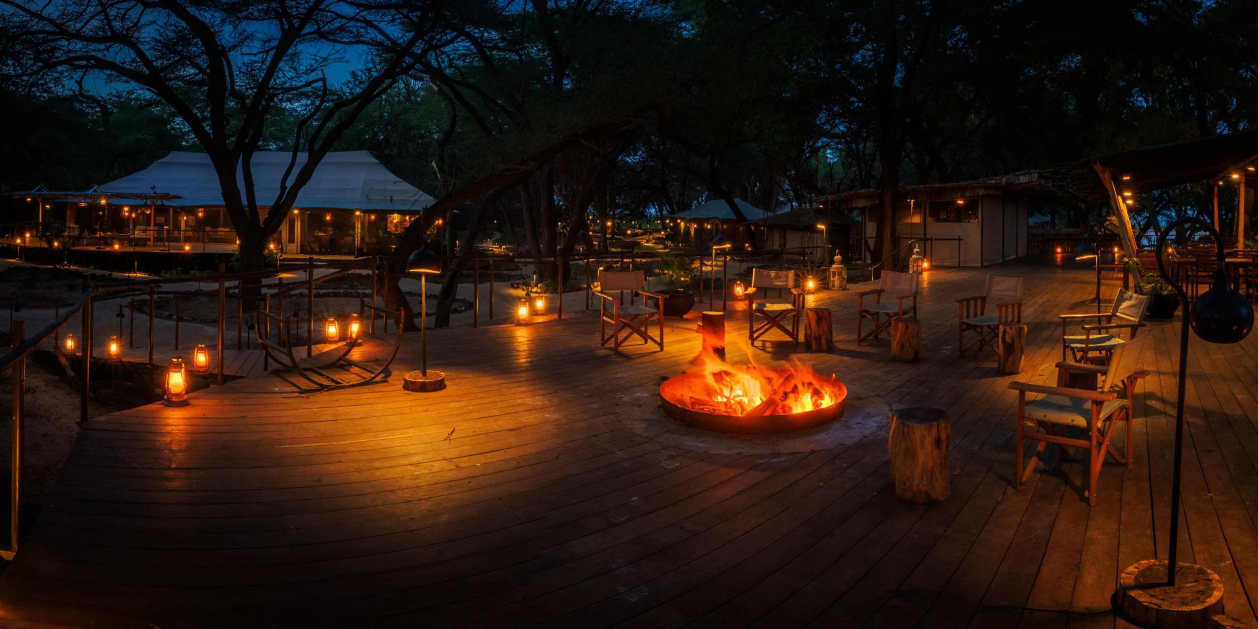 The camp's deck lit at night with a fire