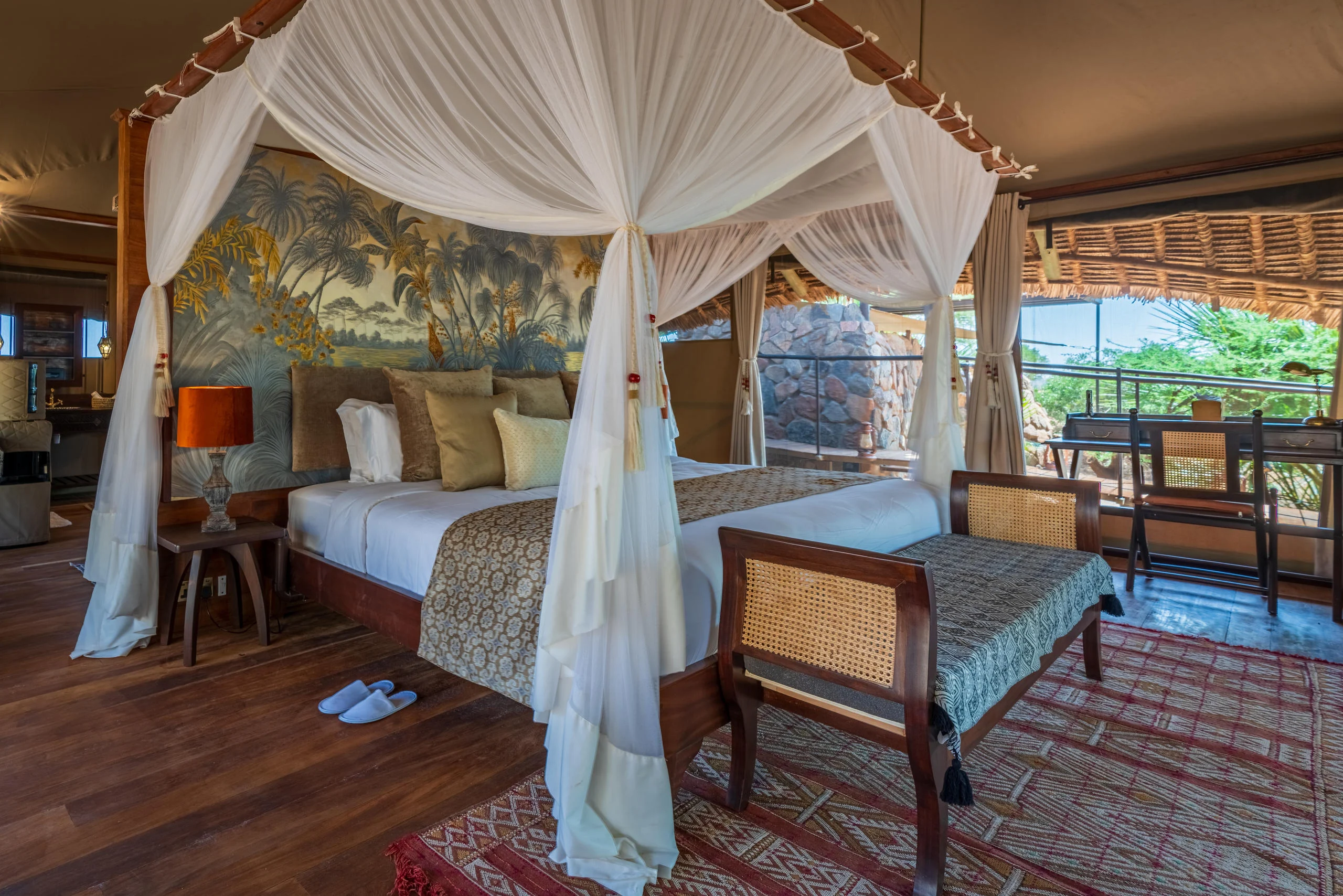 A tent bedroom with a draped bed and a red rug