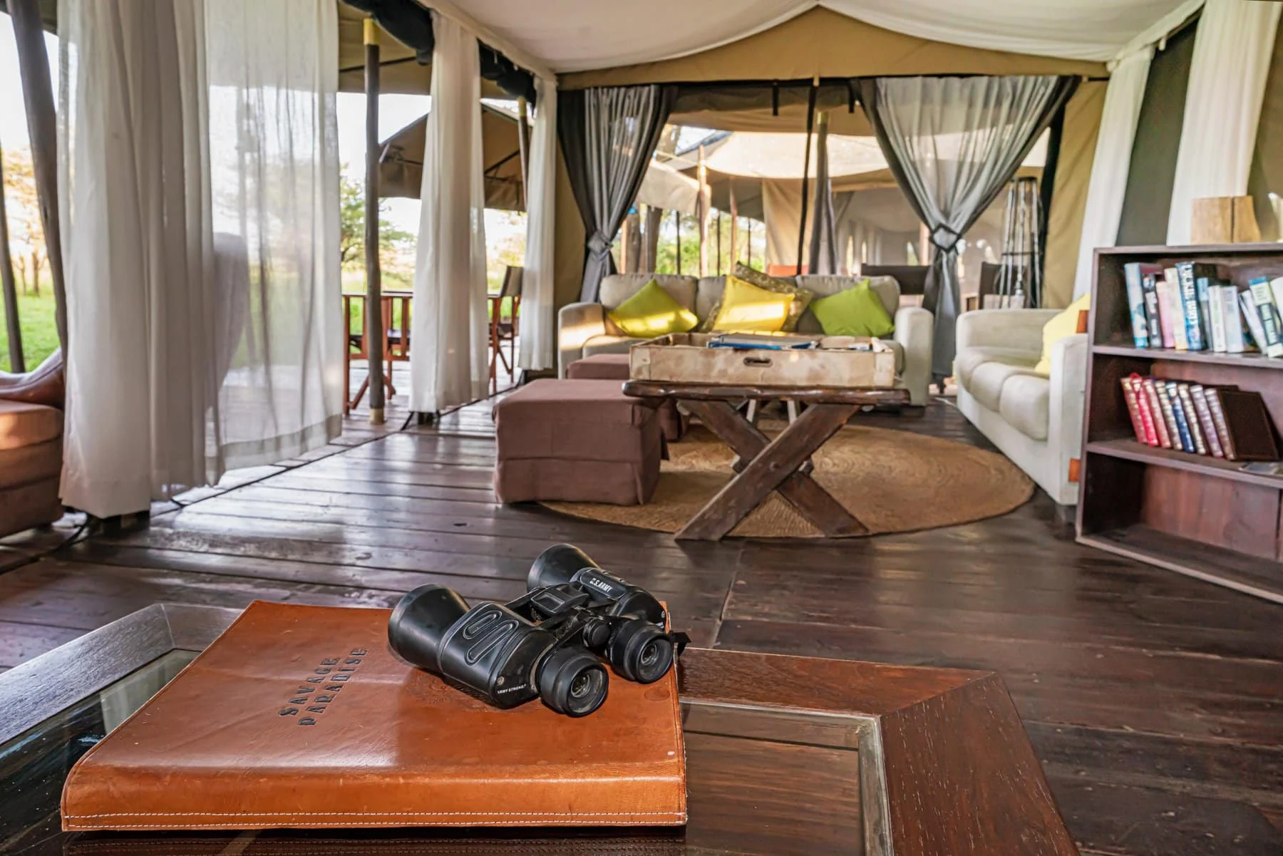 The lounge tent with binoculars on the table and a bookshelf