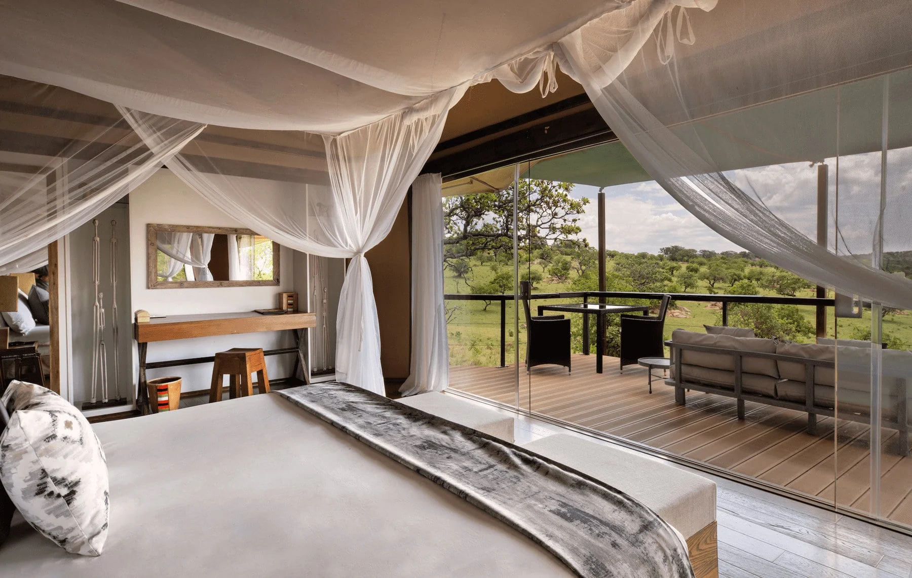A bedroom with a draped bed and glass doors onto the deck