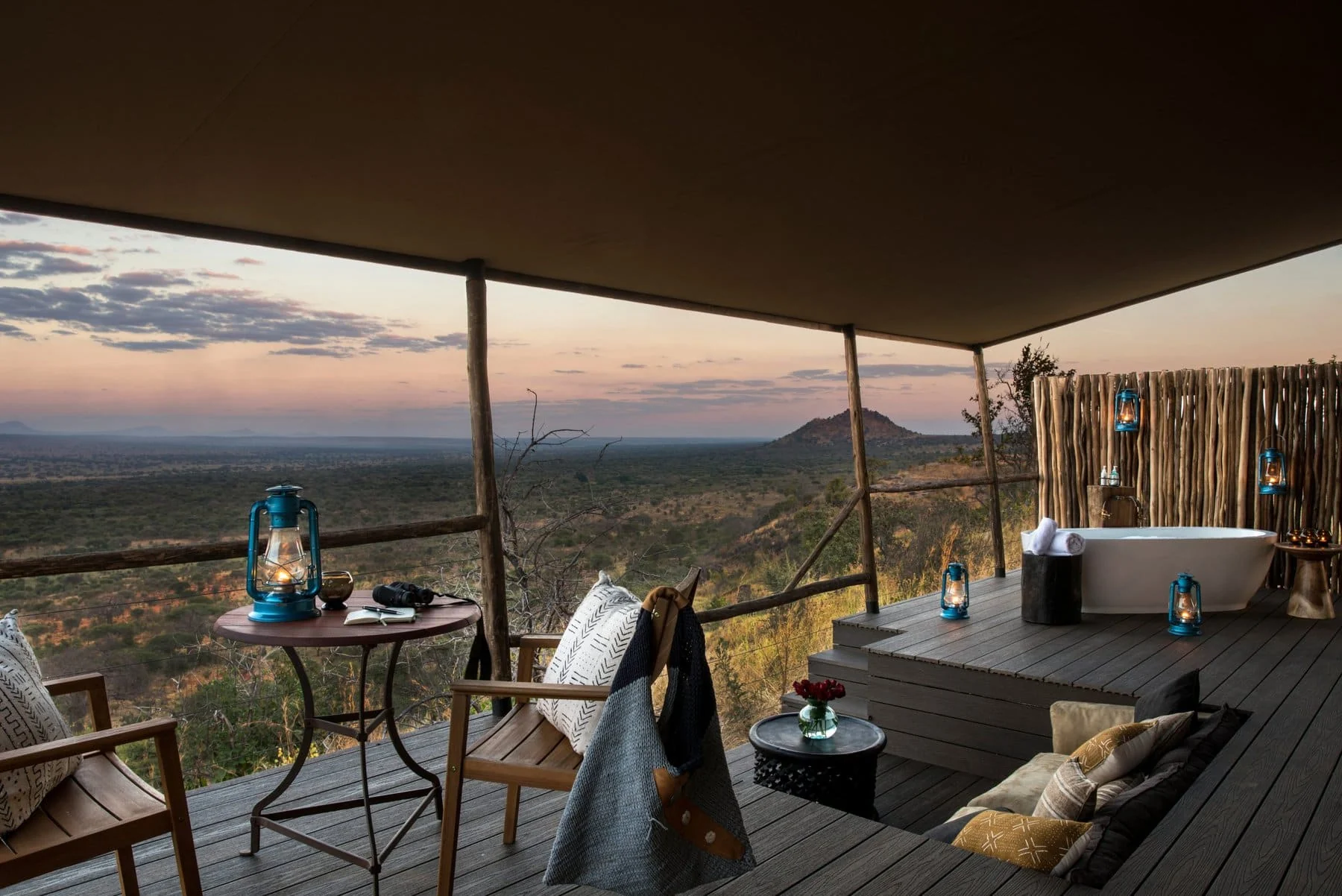 A suite deck at dusk with lanterns and a daybed