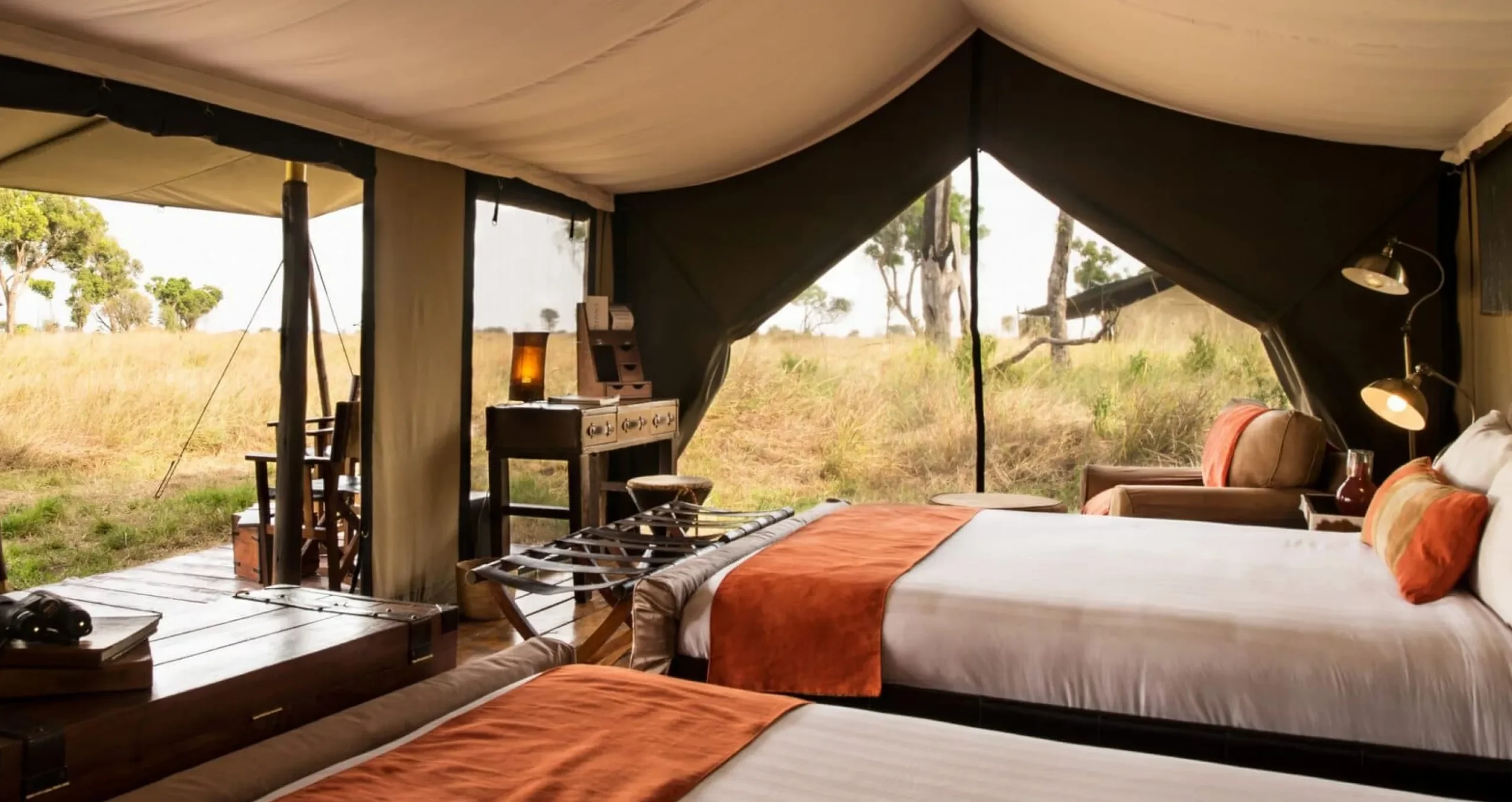 A tent bedroom with twin beds and the plains beyond