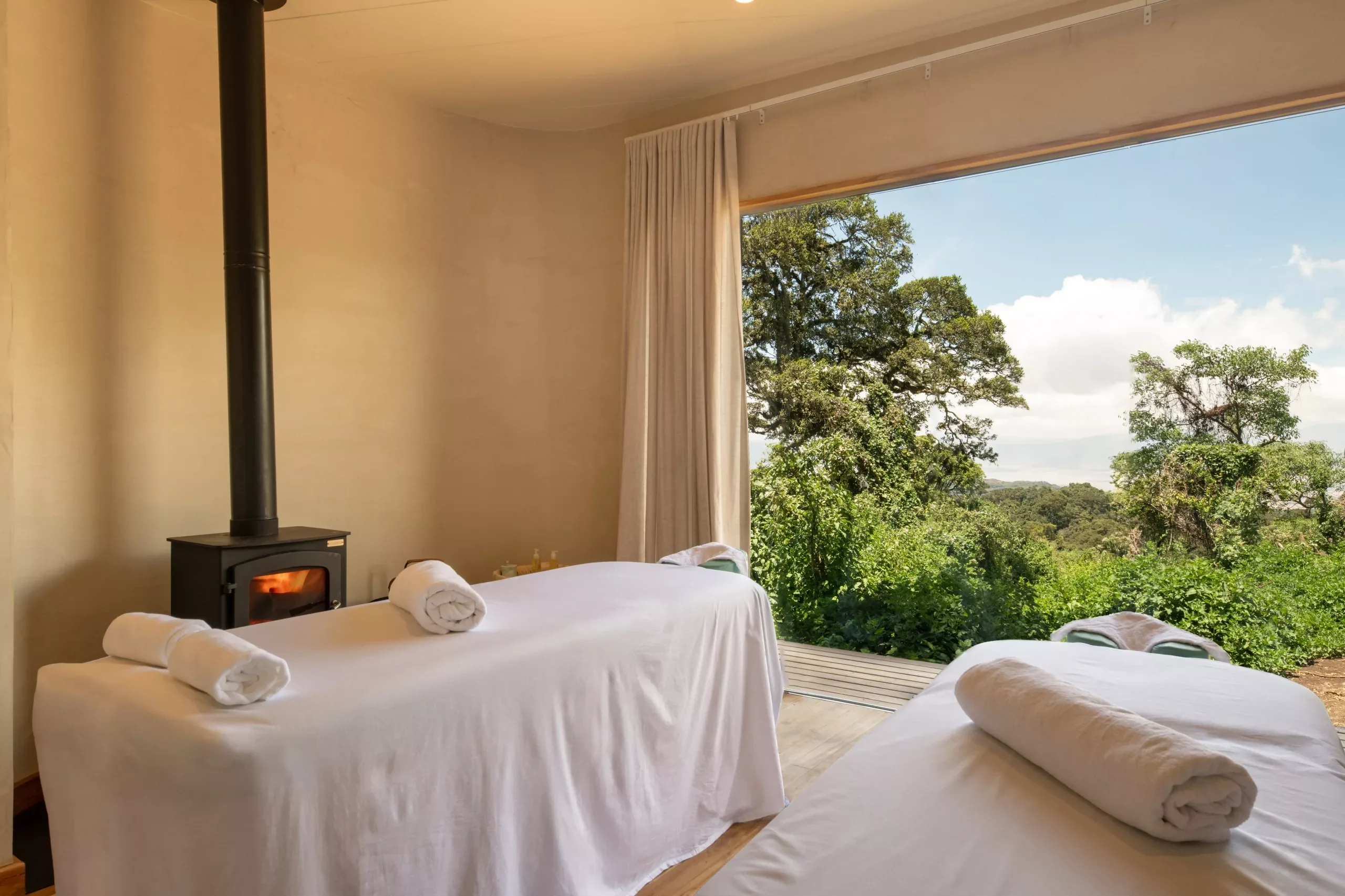 Massage beds beside a window onto the forest