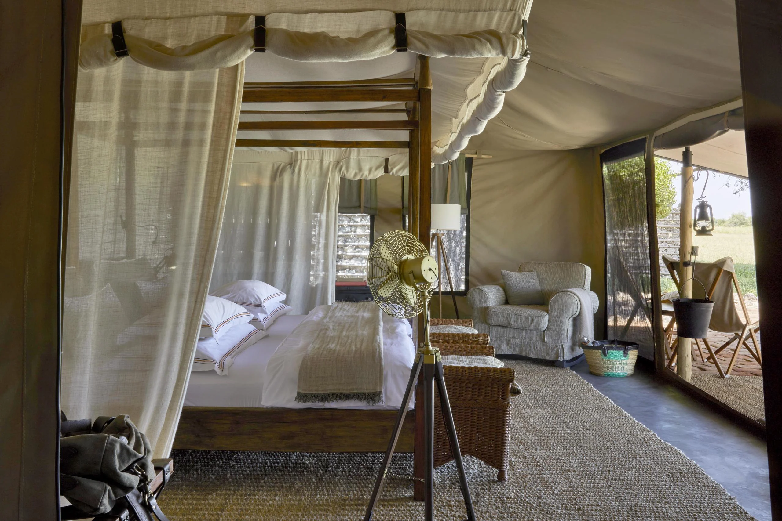 A tent bedroom with a draped bed and a desk
