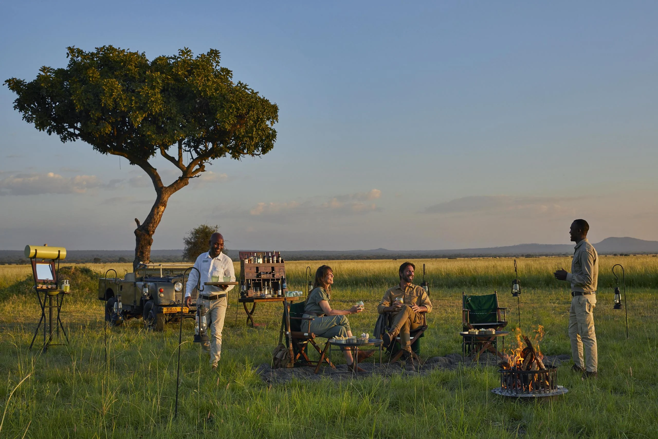 Guests at sundowners beneath a tree on the plains