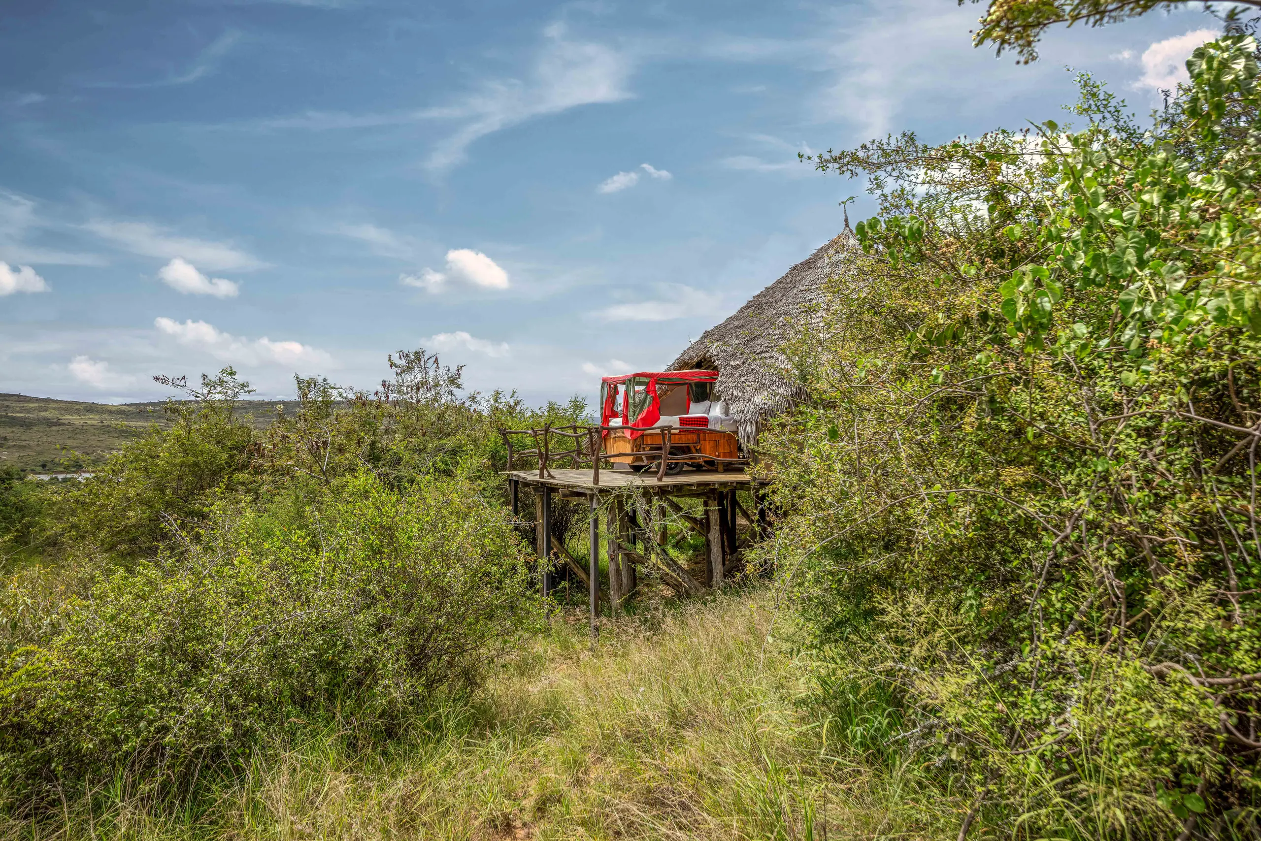 A red-draped bed on a raised open deck at Loisaba Star Beds