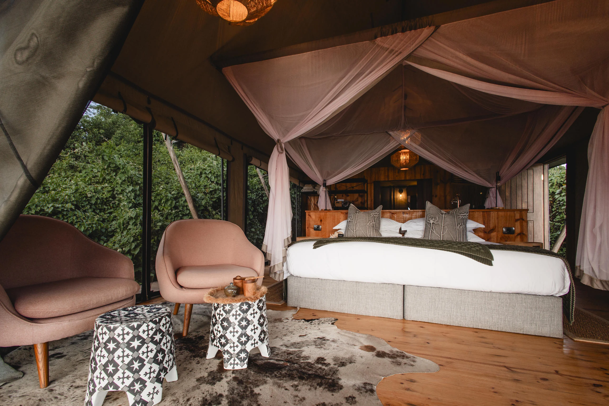 A tent bedroom with a canopied bed and armchairs