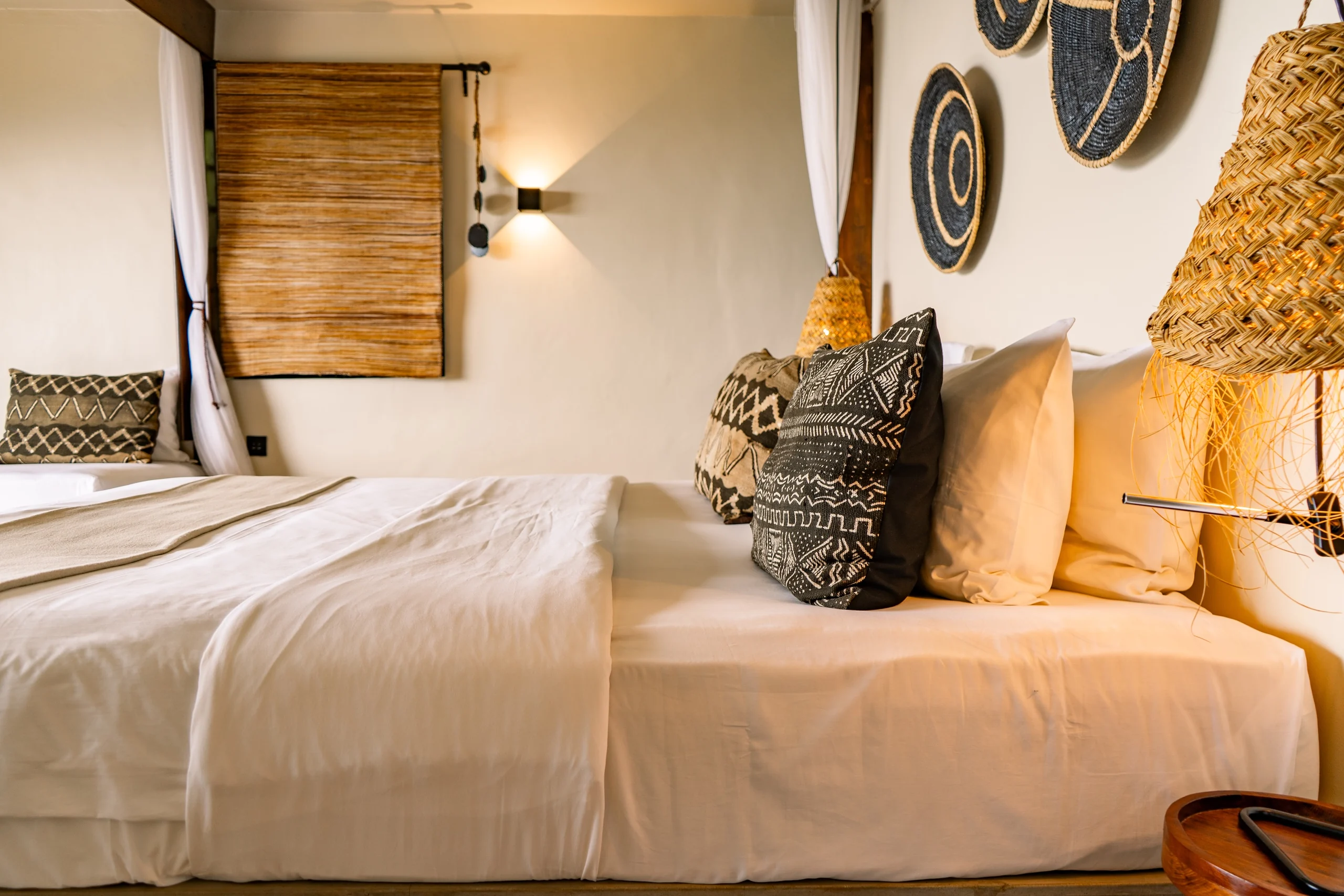 A bed with patterned cushions and woven wall hangings