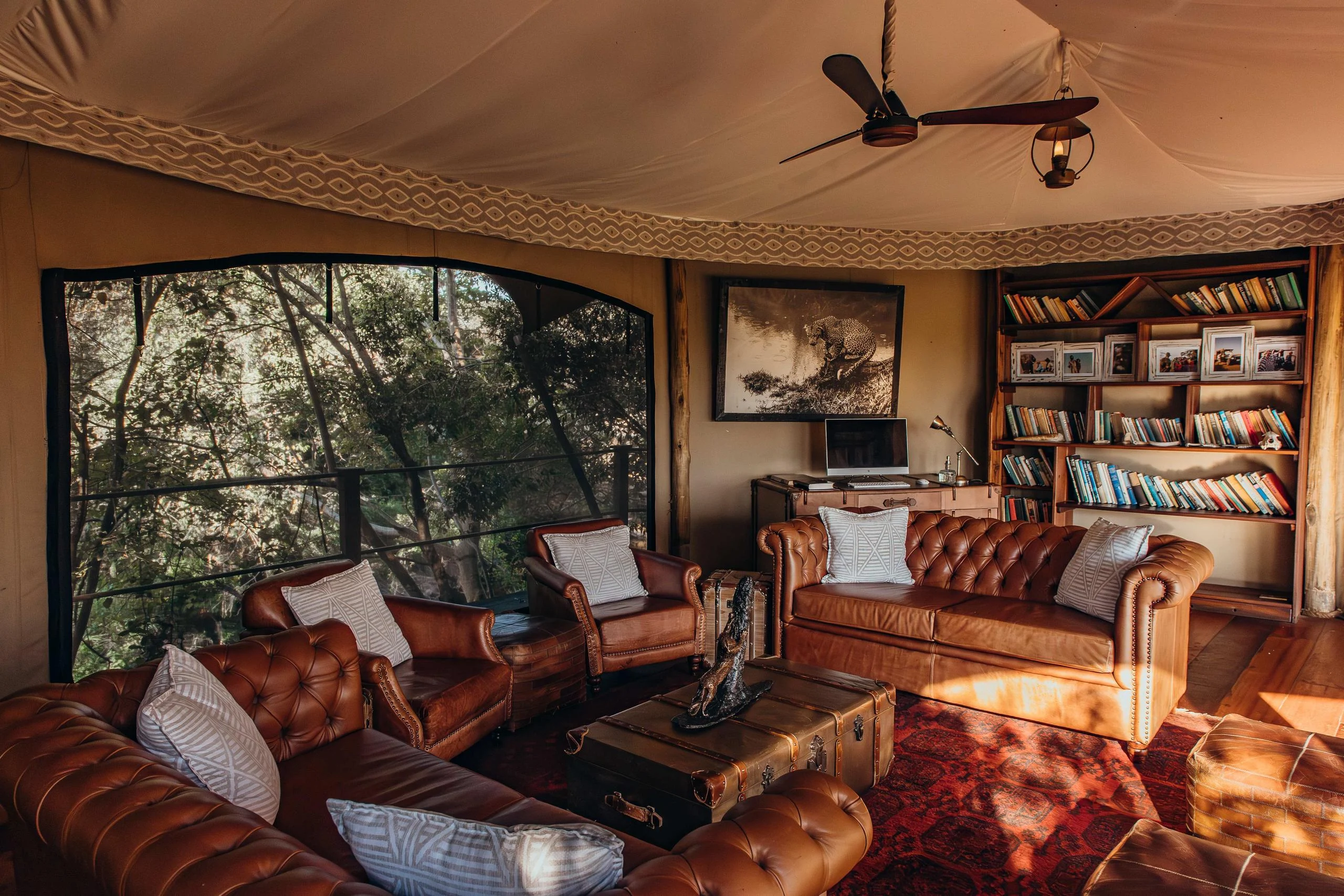 A tent sitting room with a leather sofa and bookshelves