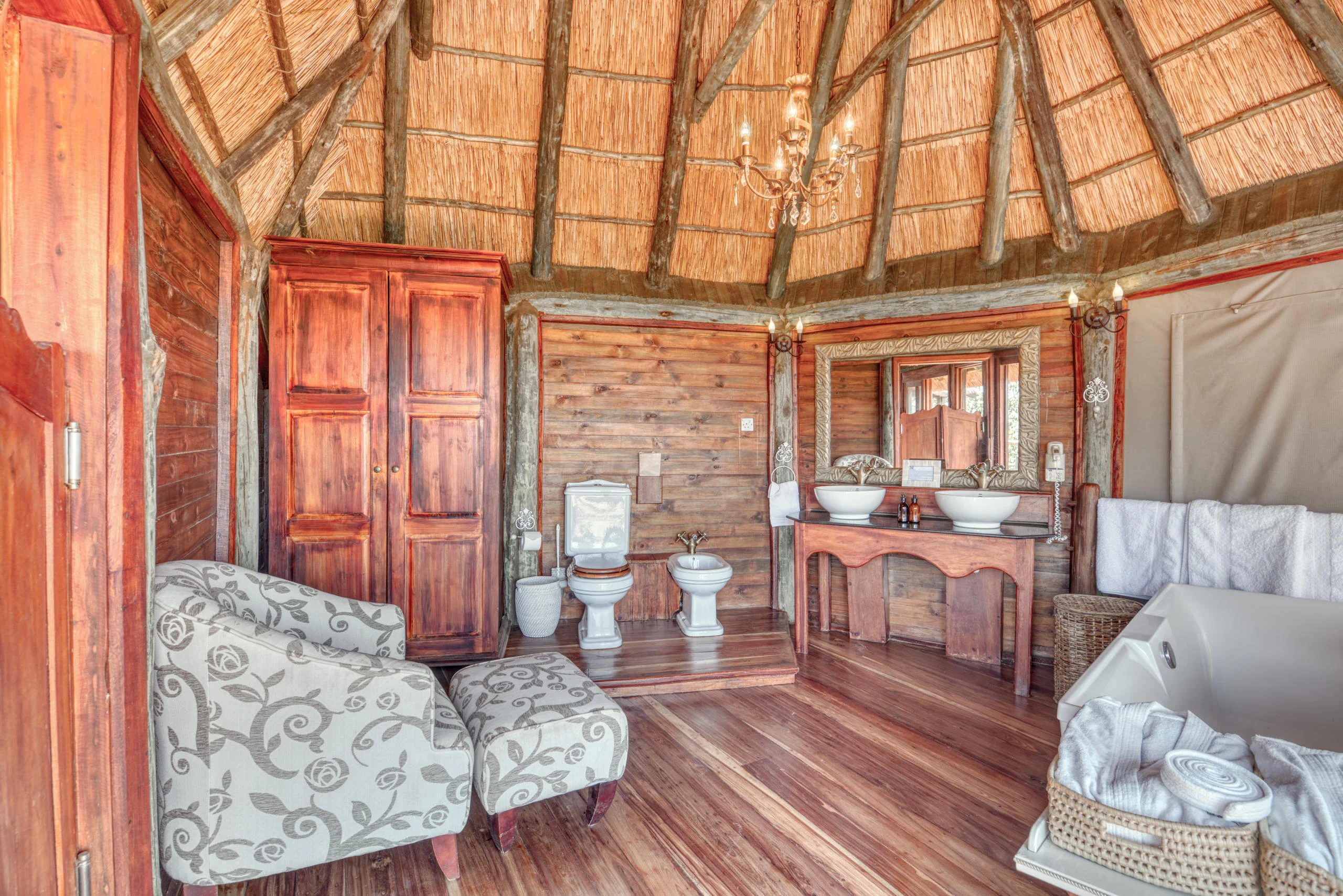 A thatched room with a sitting area and bathroom