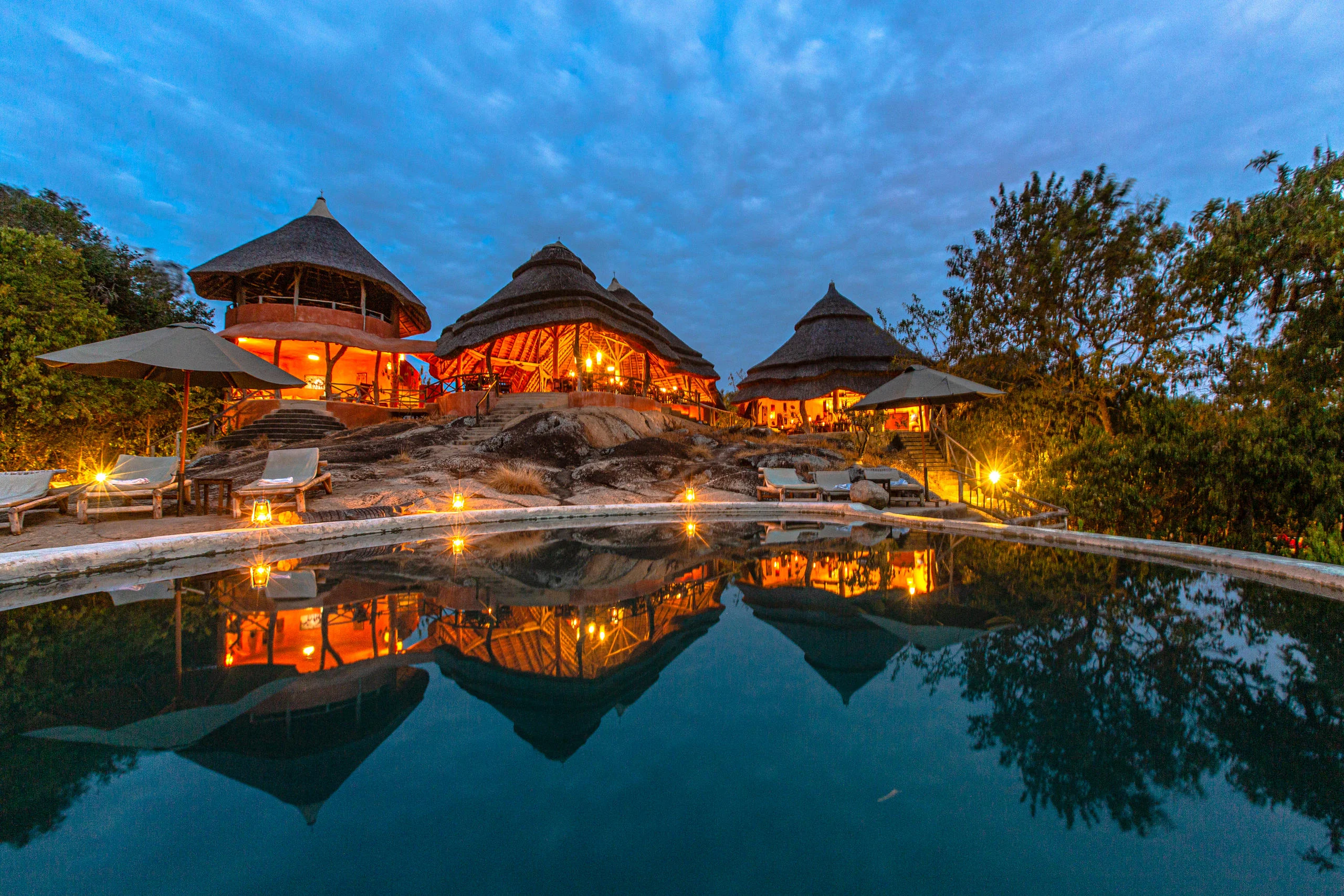 The pool and thatched bandas lit at dusk