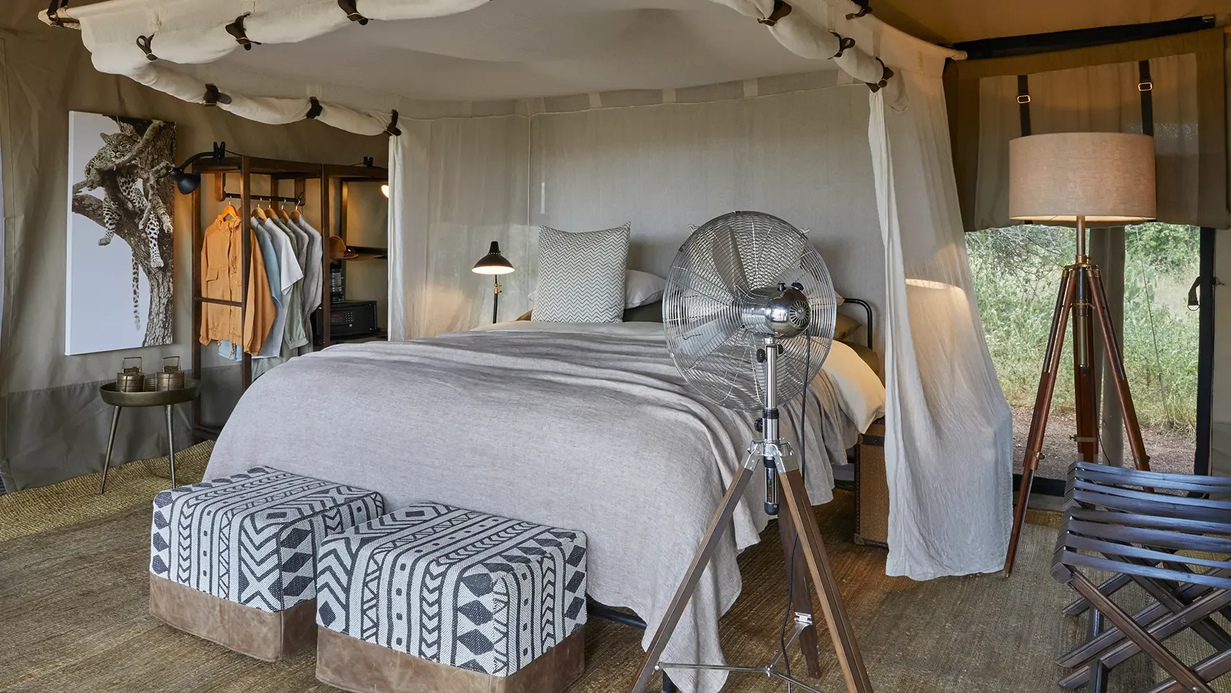 A tent bedroom with a canopied bed and patterned stools