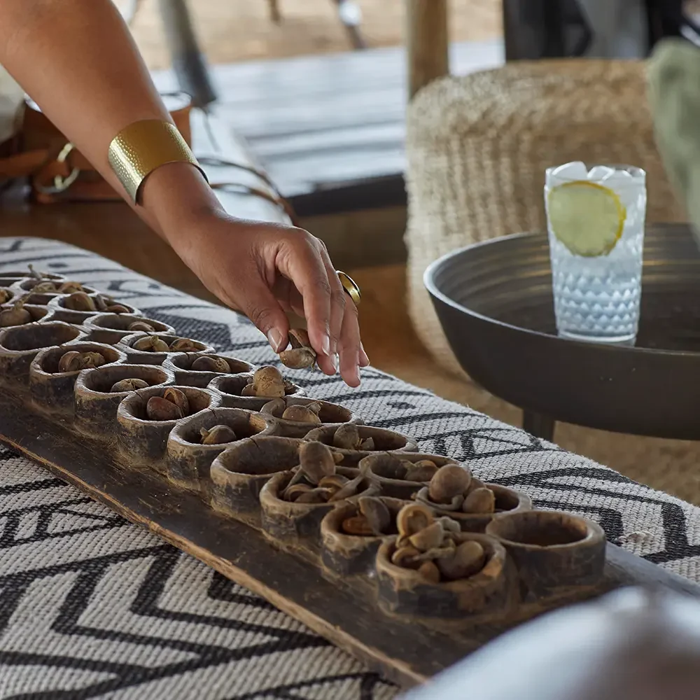A game of bao on a table beside a drink