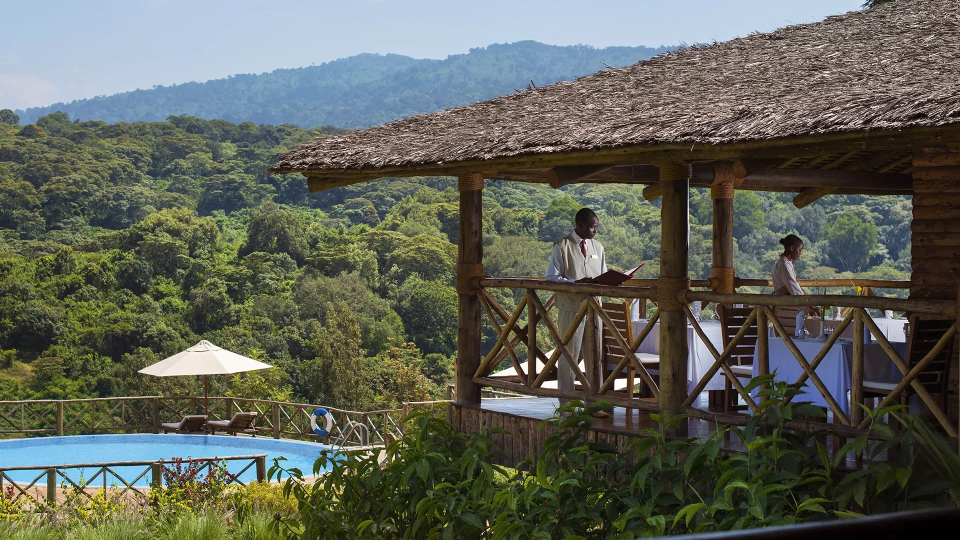 The thatched main building and pool on the forested slope