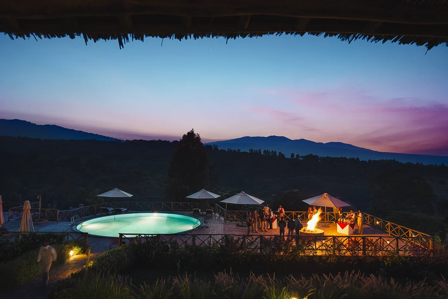 The pool lit at dusk with the hills beyond