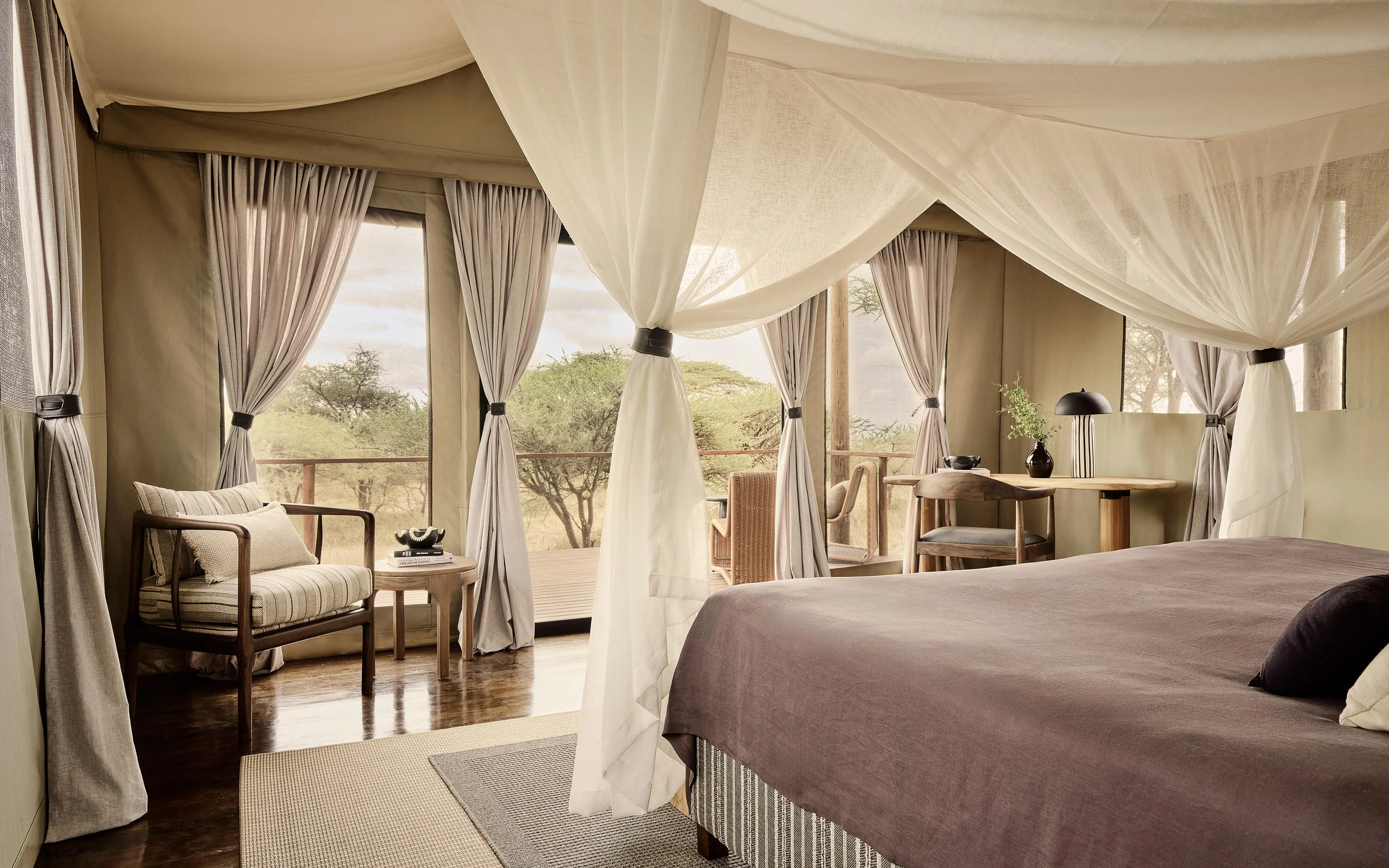 A tent bedroom with a draped bed and a desk by the window