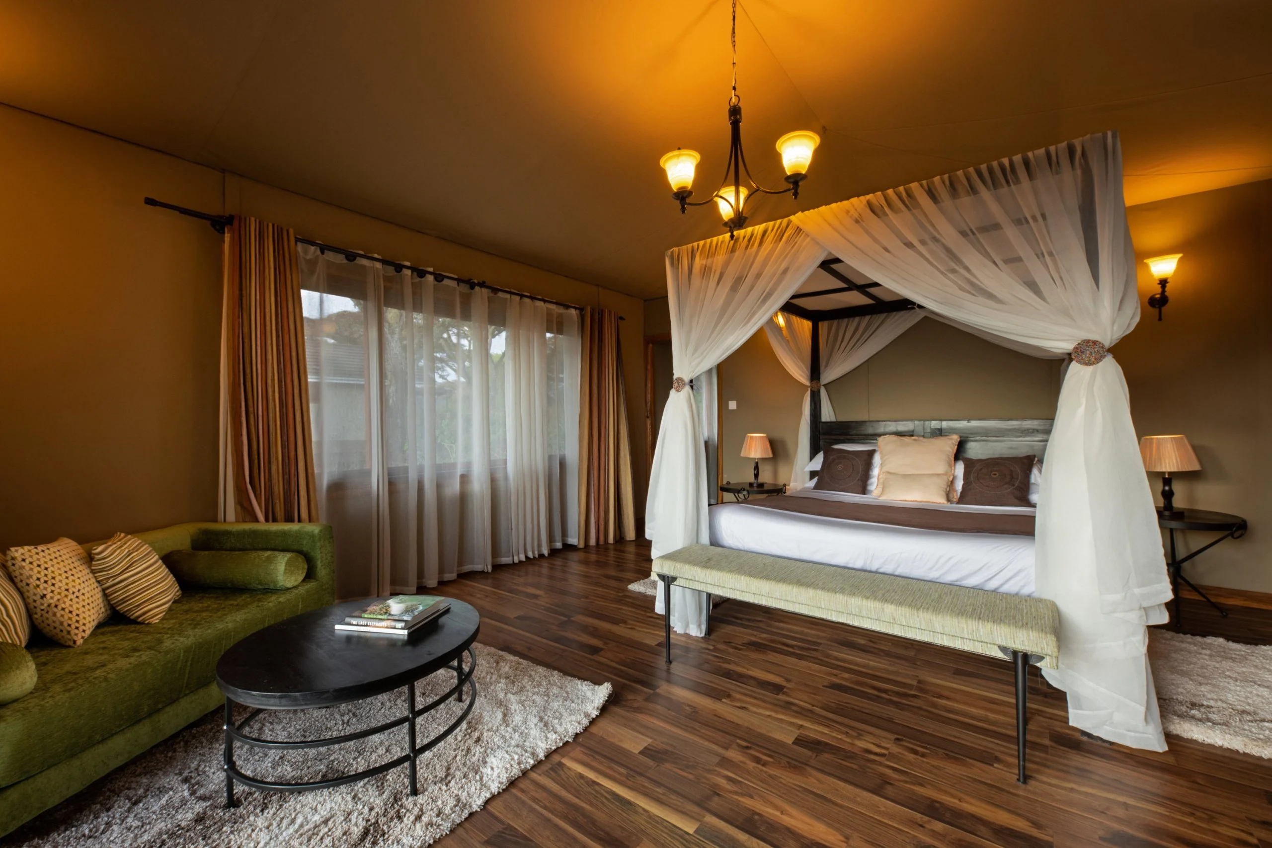 A bedroom with a draped four-poster bed and a green sofa