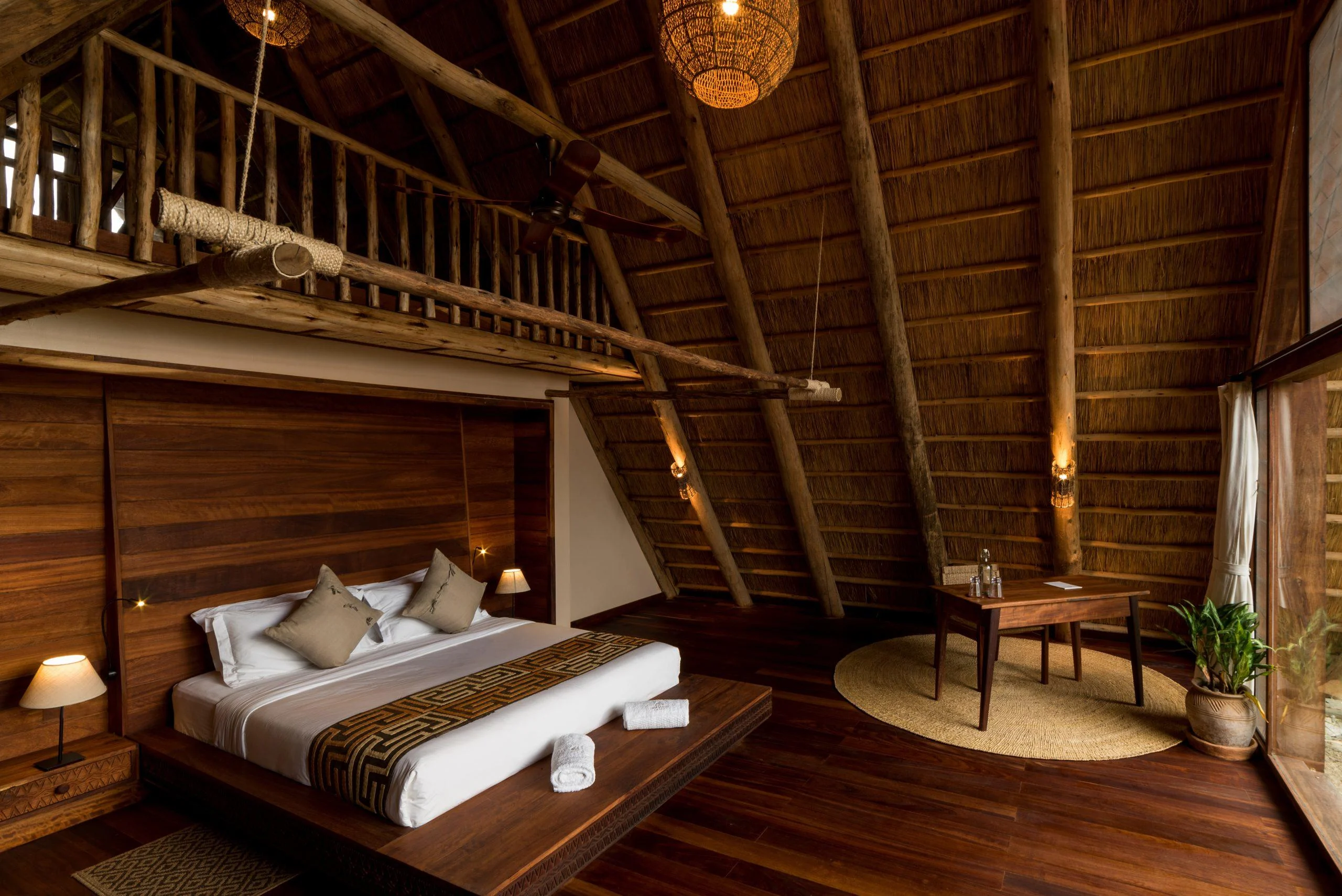 A bedroom under a high thatched roof