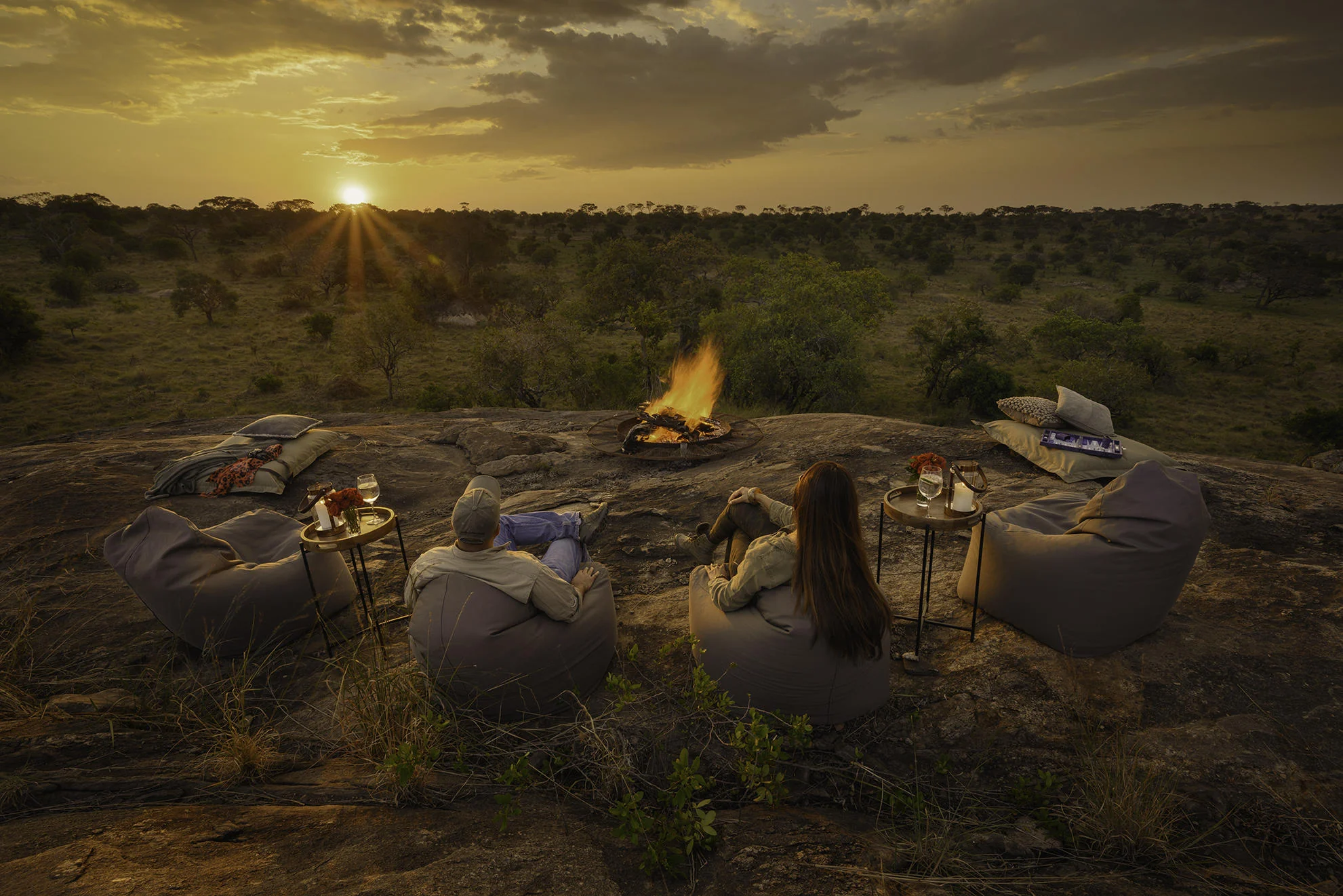 Guests around a fire on the rocks at sunset