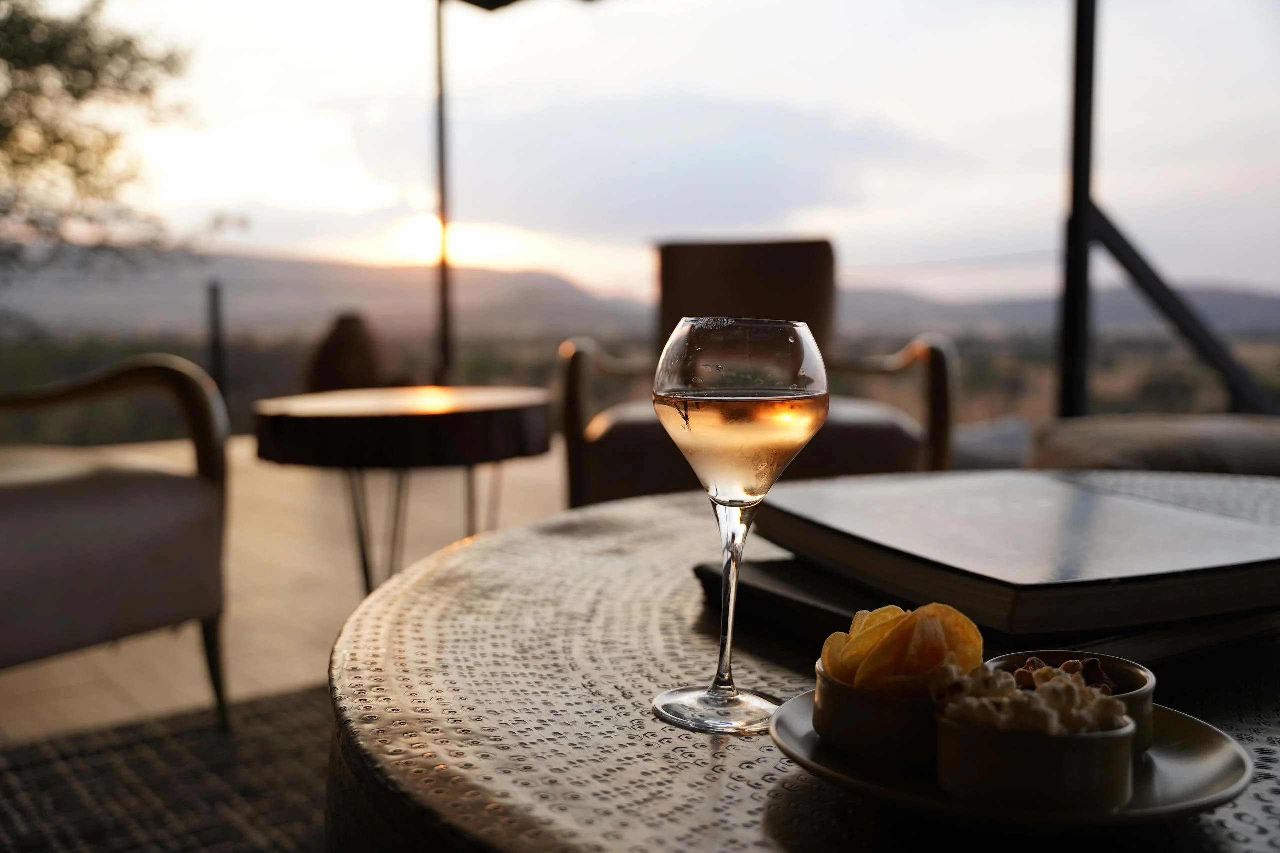 A glass of wine on a table at sunset