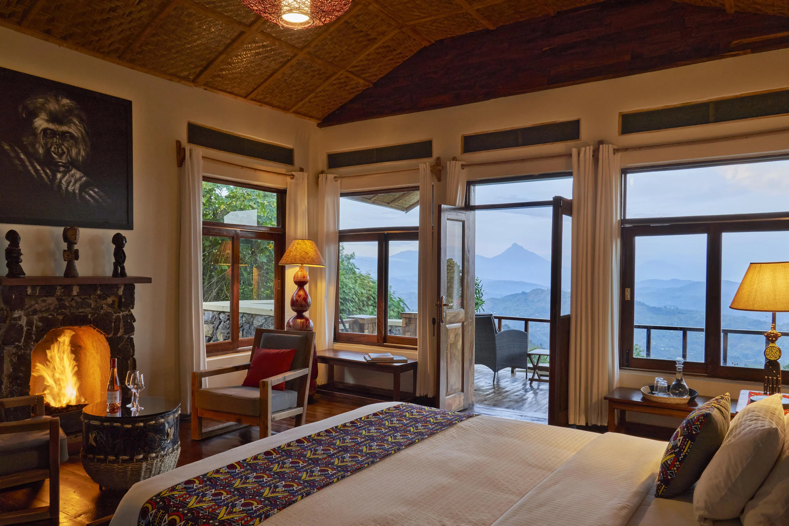 A cottage bedroom with a fireplace and windows onto the hills