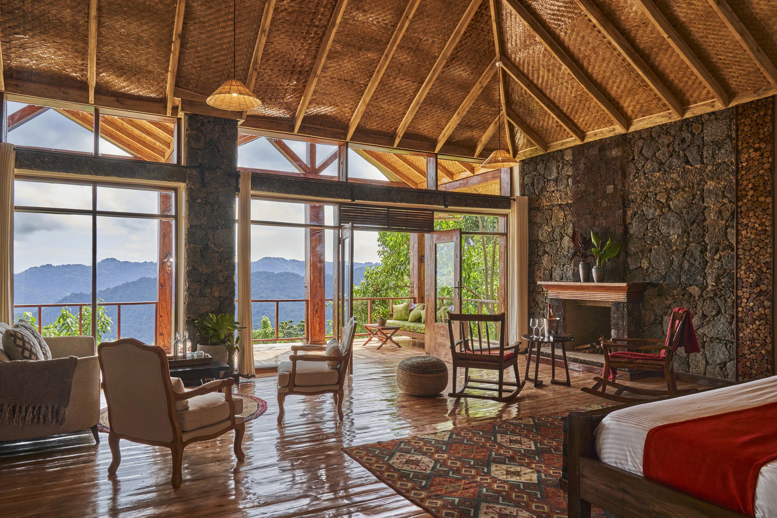 A suite with a stone wall and a bed looking out to the view