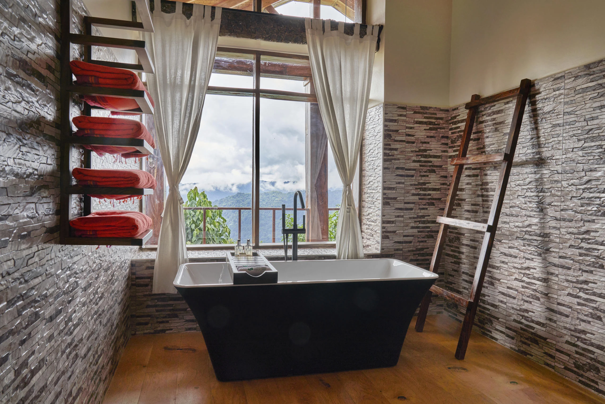 A bathroom with a black bath beneath the window