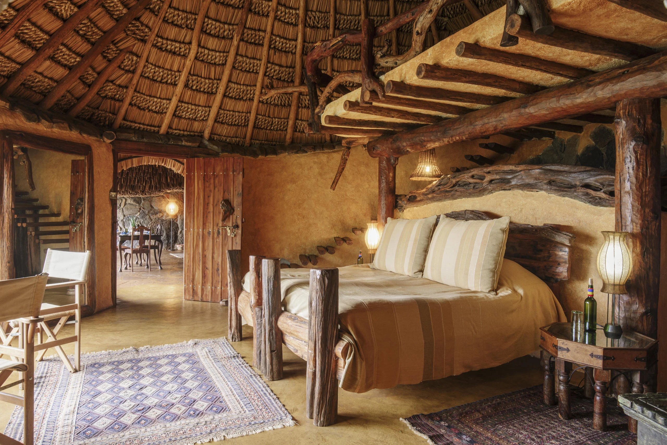 A bedroom under thatch with a timber four-poster bed