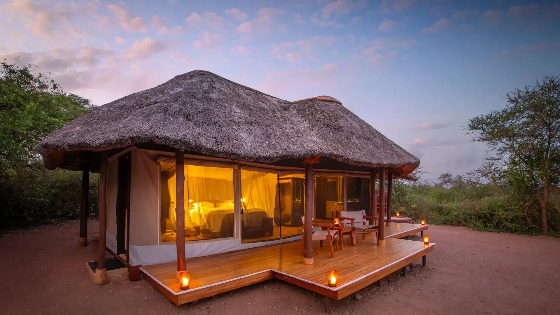 A thatched guest tent lit in the evening