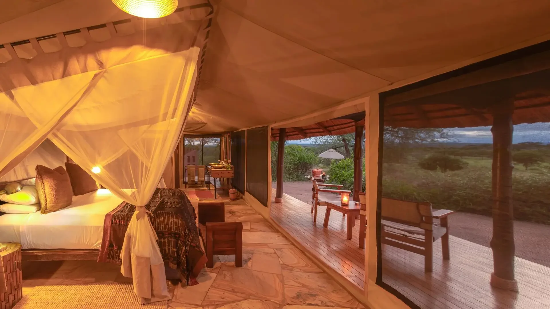 A tent bedroom with a canopied bed and the view beyond