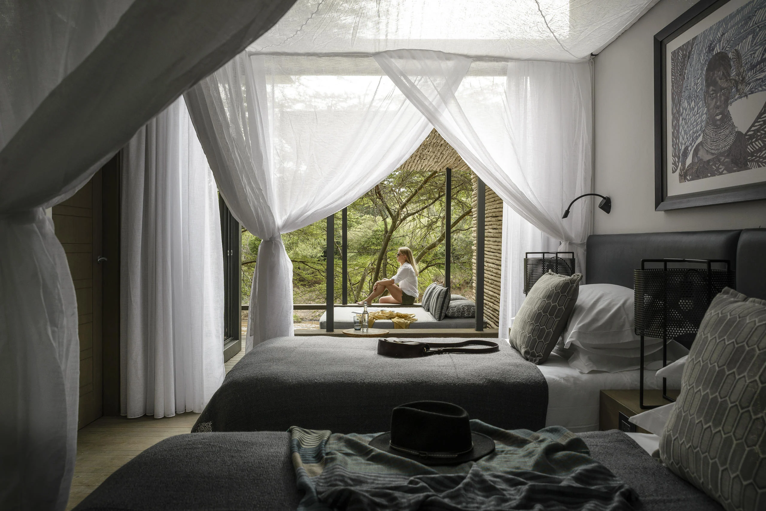 A bedroom with drapes and the trees beyond