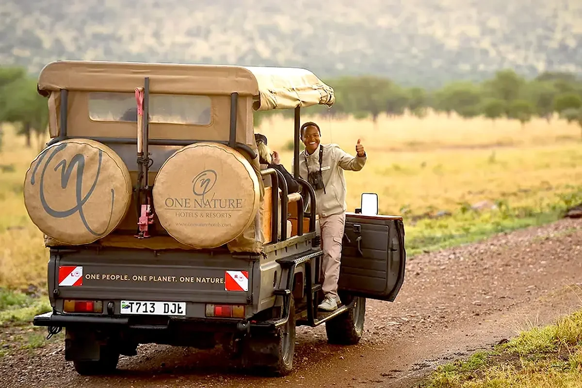 A guide beside a safari vehicle on the plains
