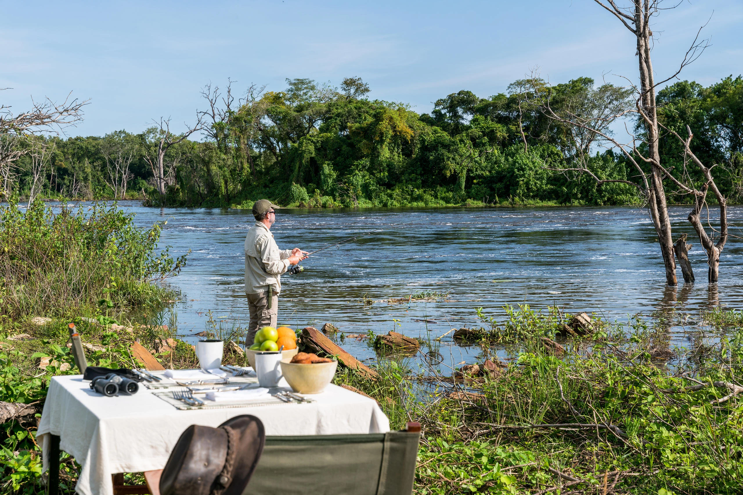 A table laid beside the river with a fisherman beyond
