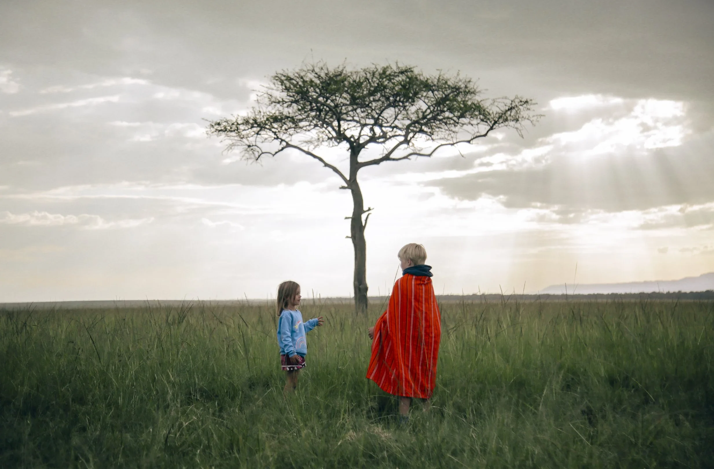 A guide and a child under a lone tree on the plains