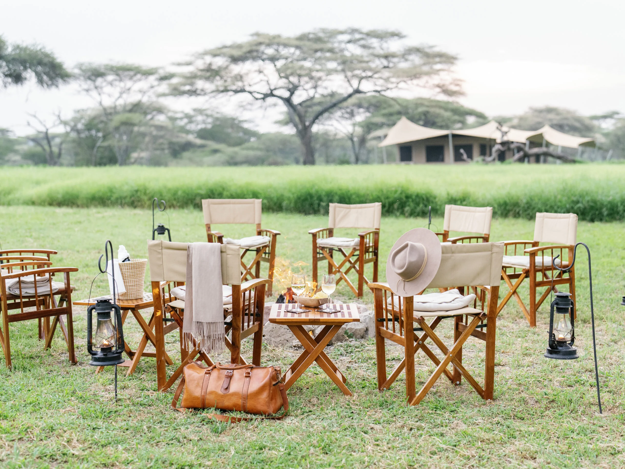 Chairs and lanterns set out for dinner in front of the tents