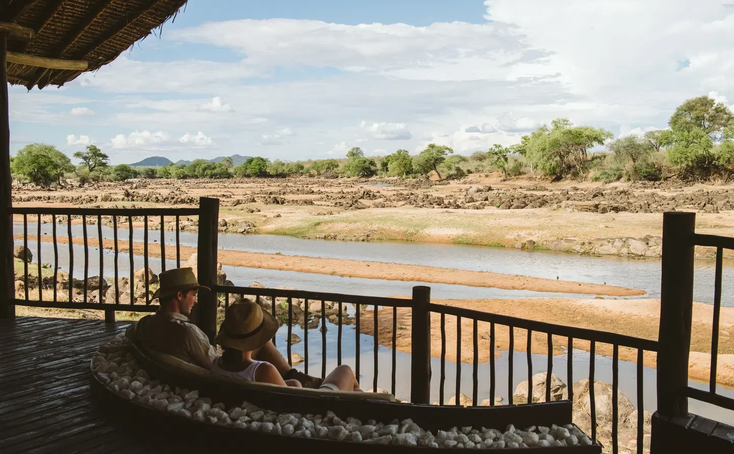 Guests on a daybed on the deck above the river