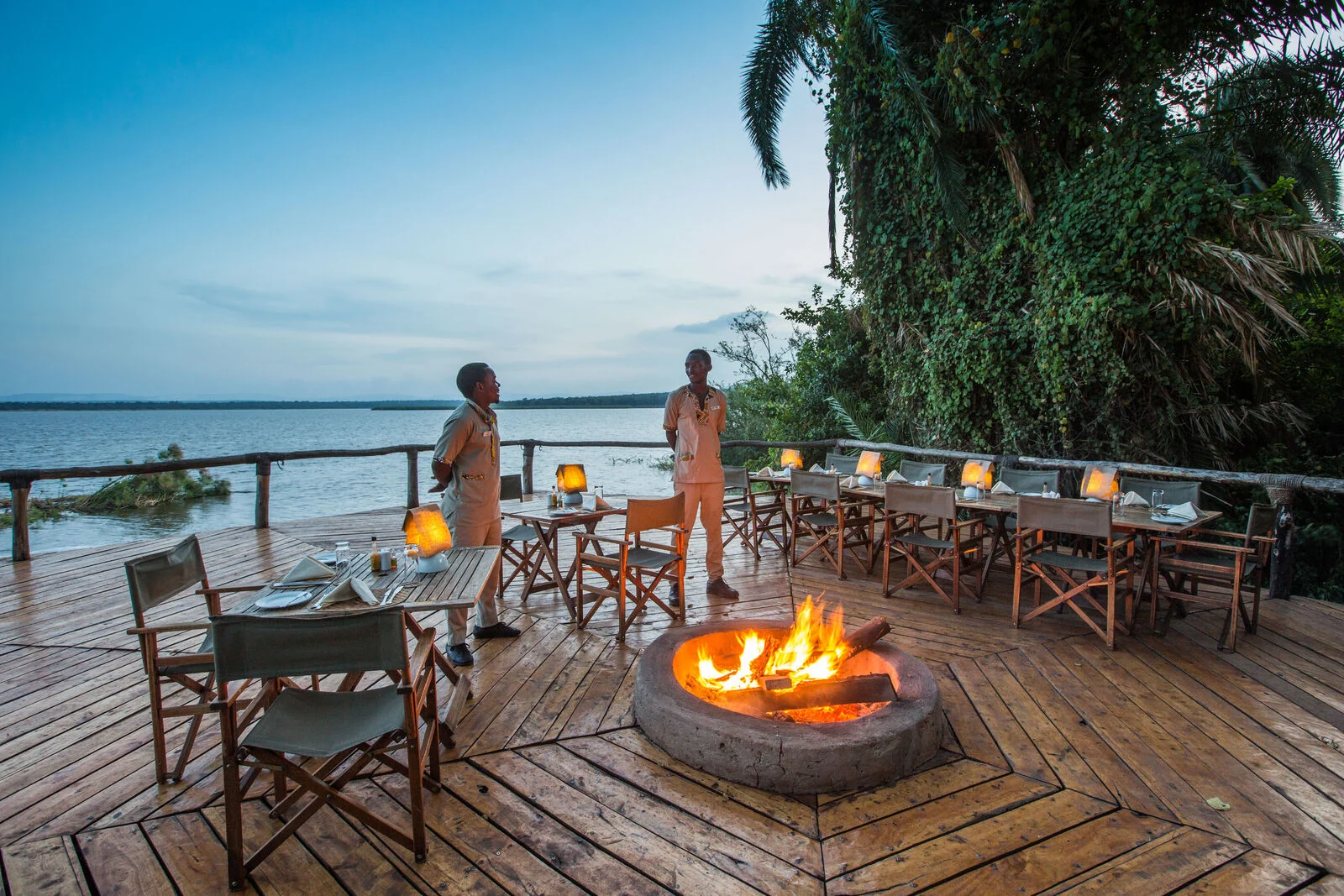 Guests beside the fire on the deck above the lake at dusk