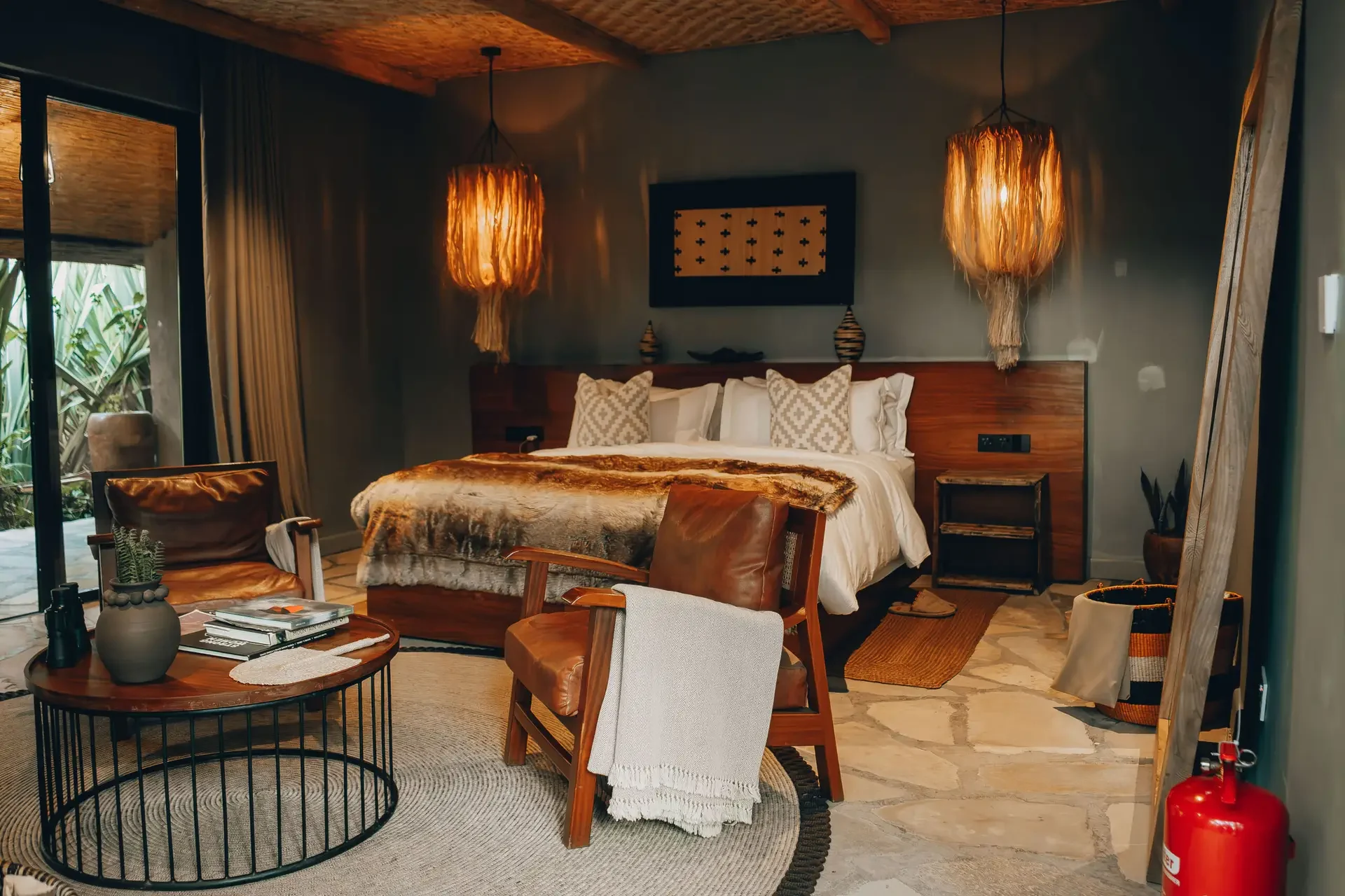 A bedroom with woven pendant lamps and a fur throw