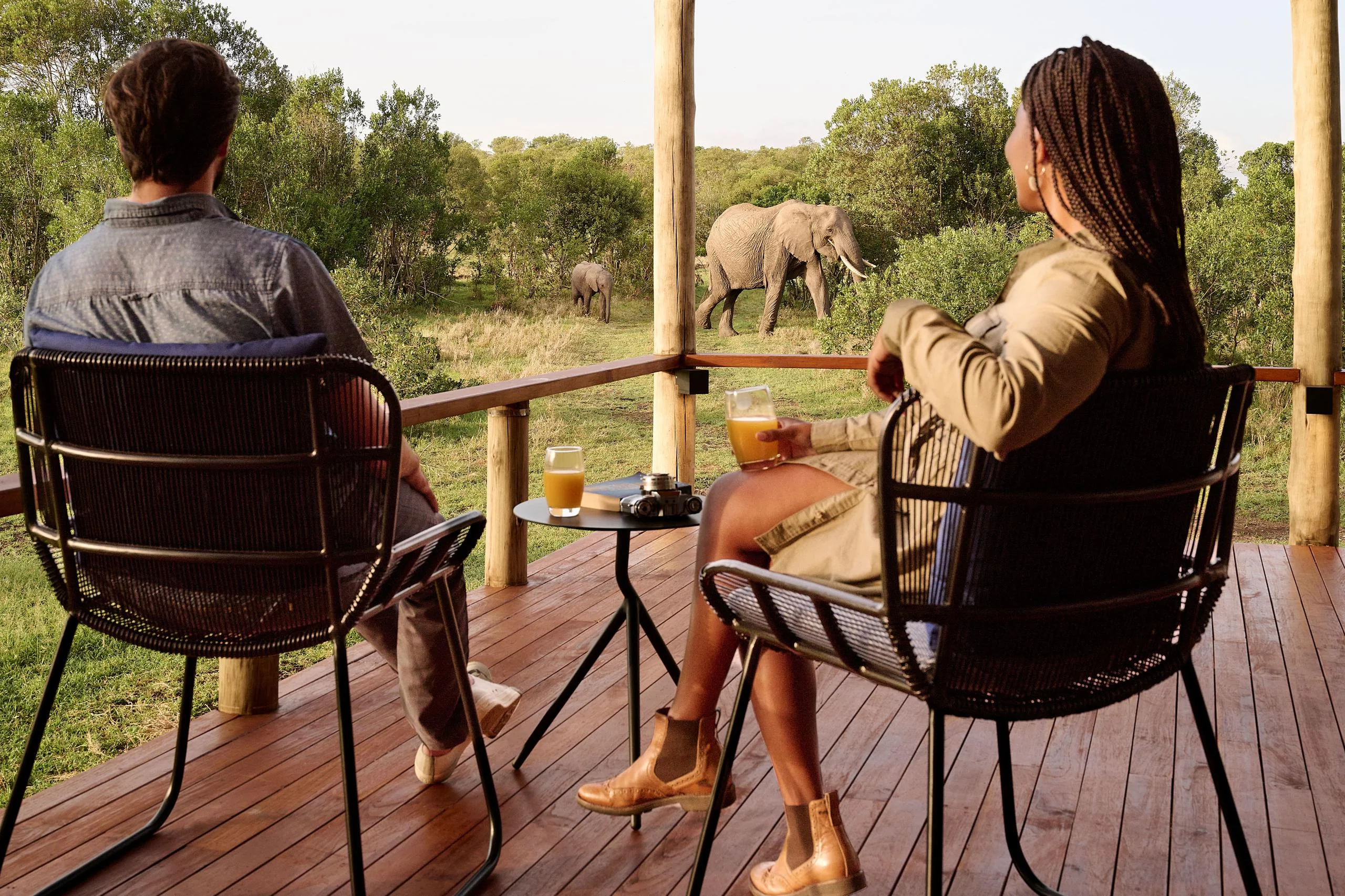 Two guests on a tent deck watching elephants