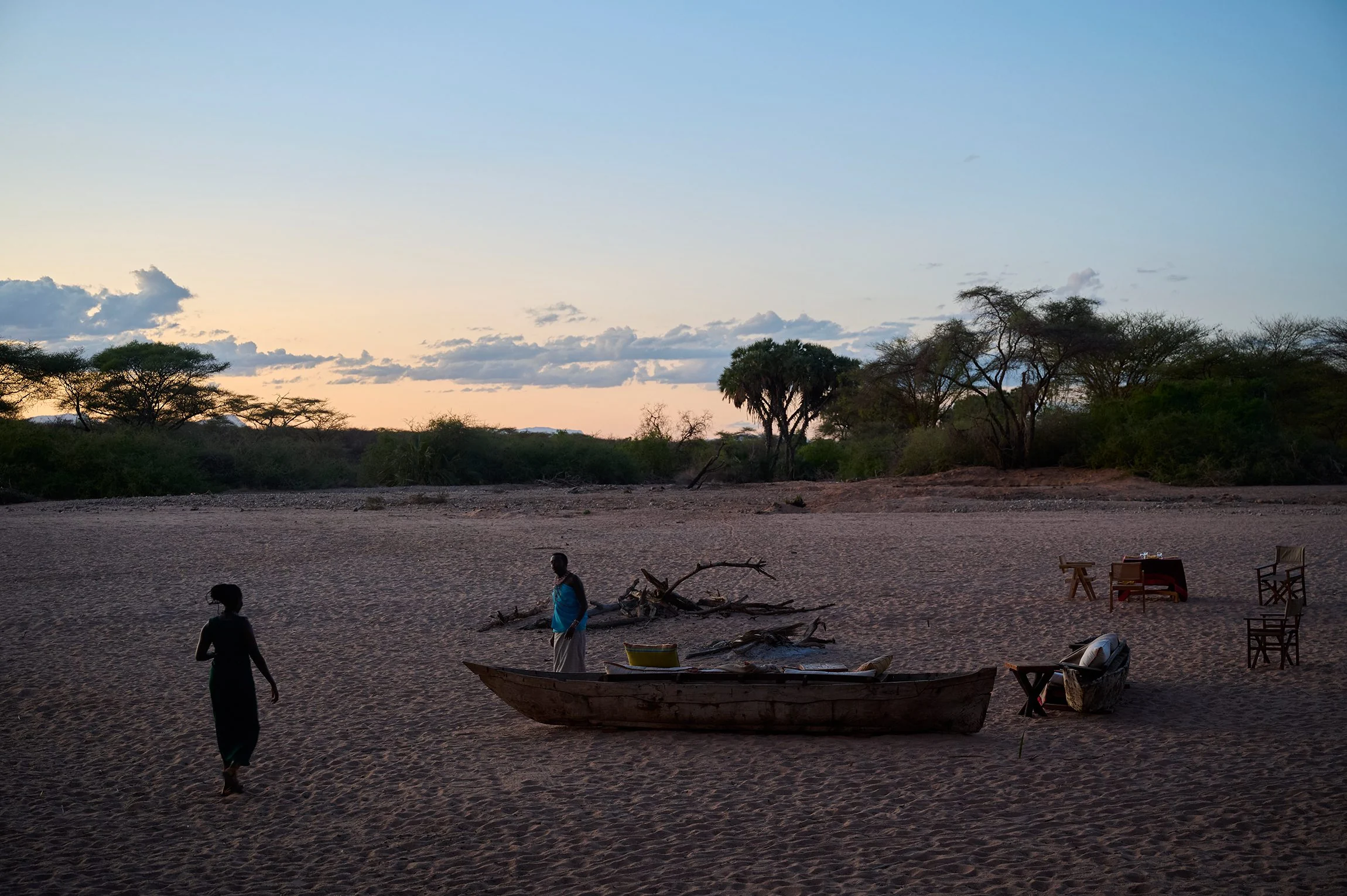 A dinner table set on the dry riverbed at dusk