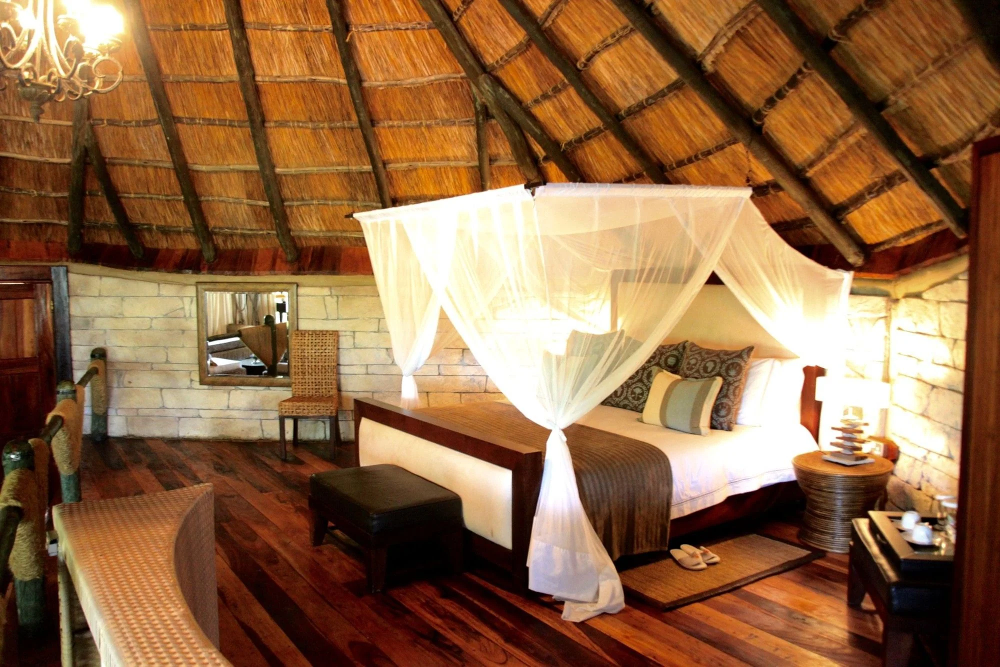 A bedroom under thatch with a draped bed