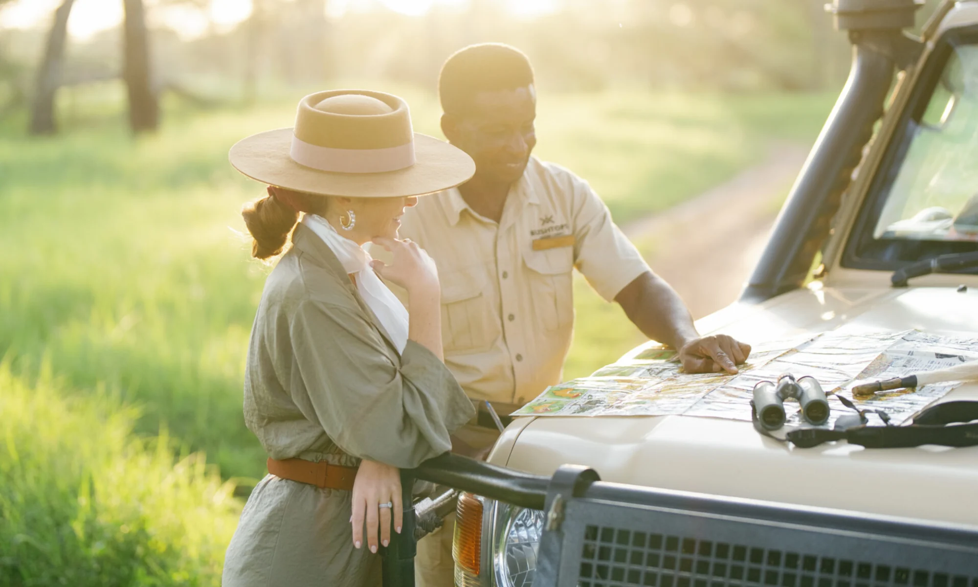 A guide and a guest looking at a map on the vehicle bonnet