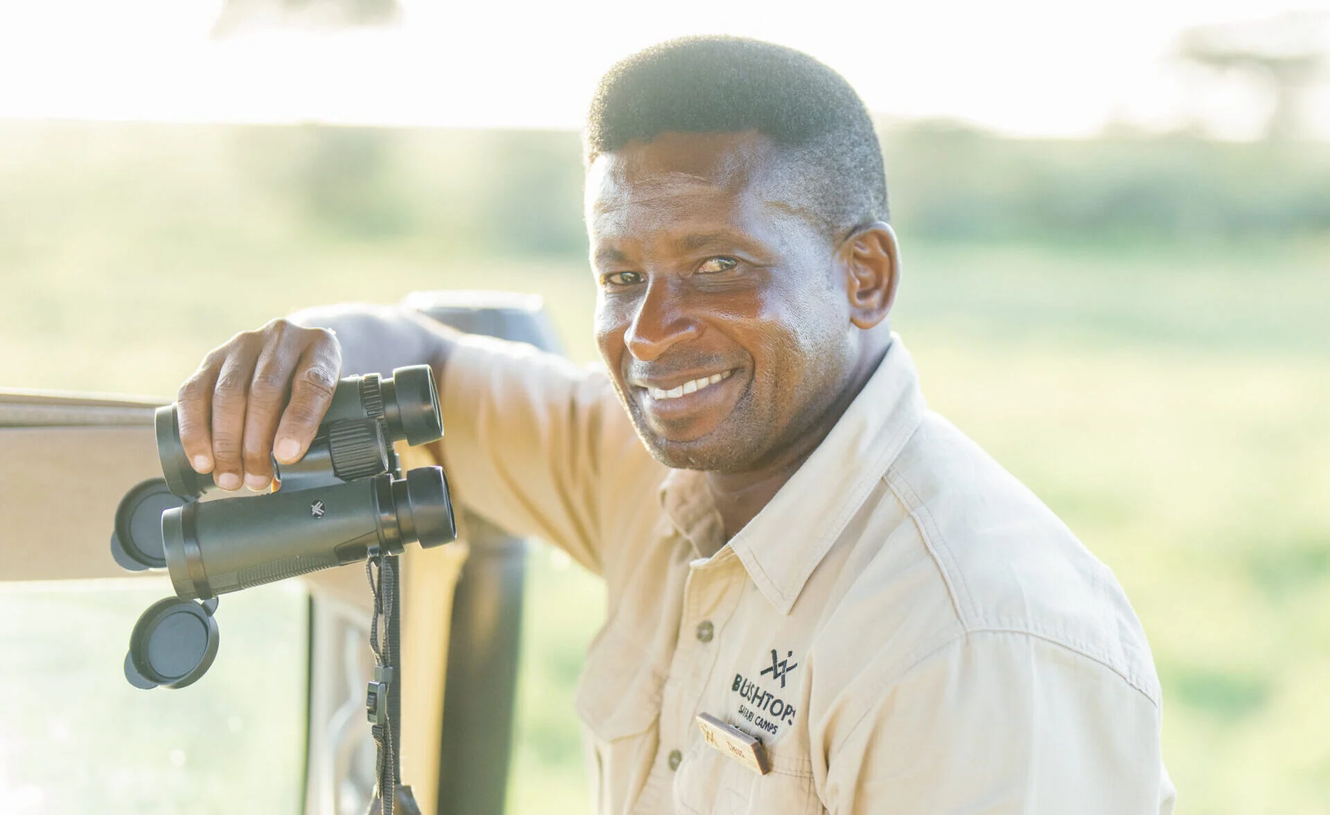 A guide with binoculars in a safari vehicle