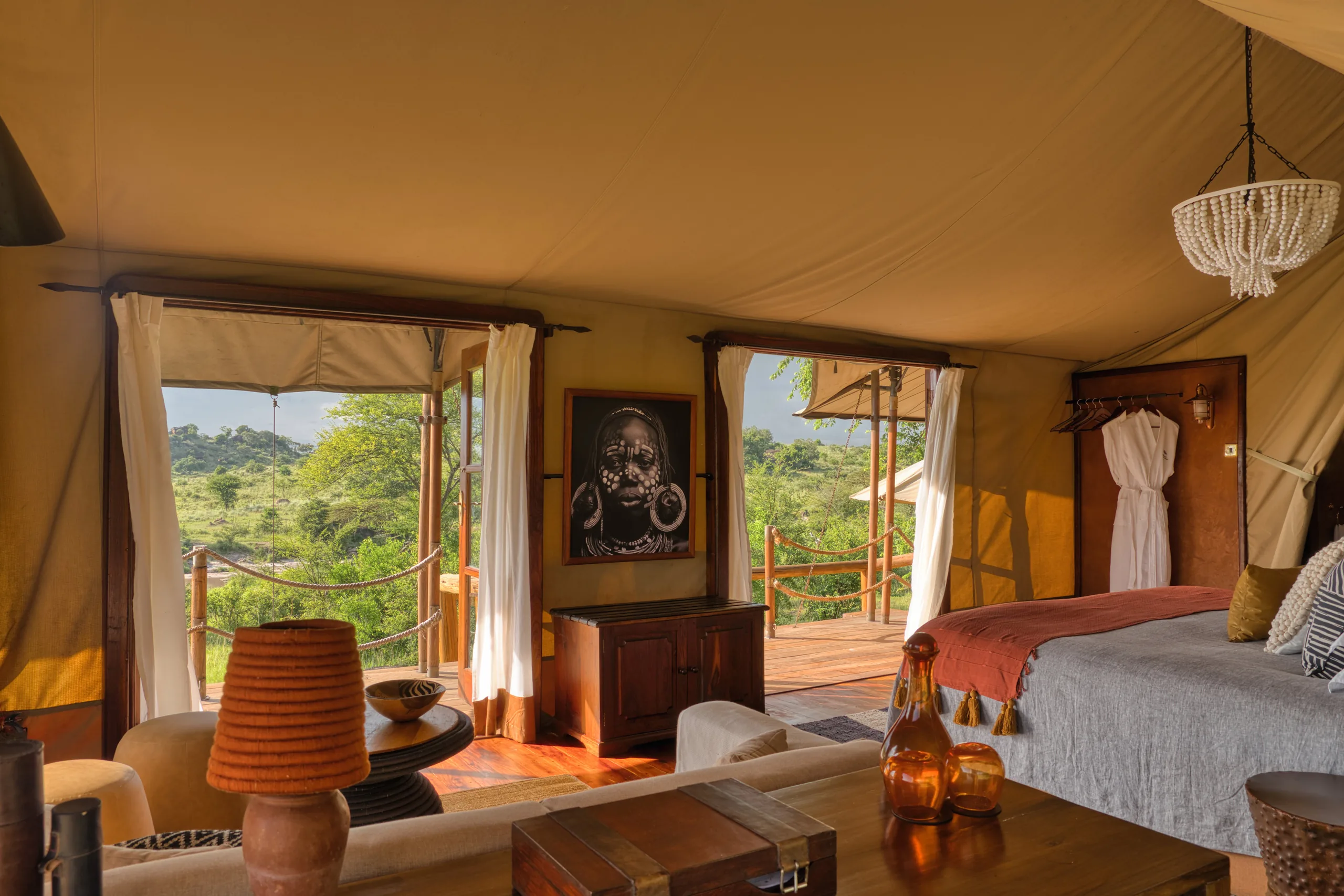 A furnished safari tent opening towards the trees at Serengeti Migration Camp