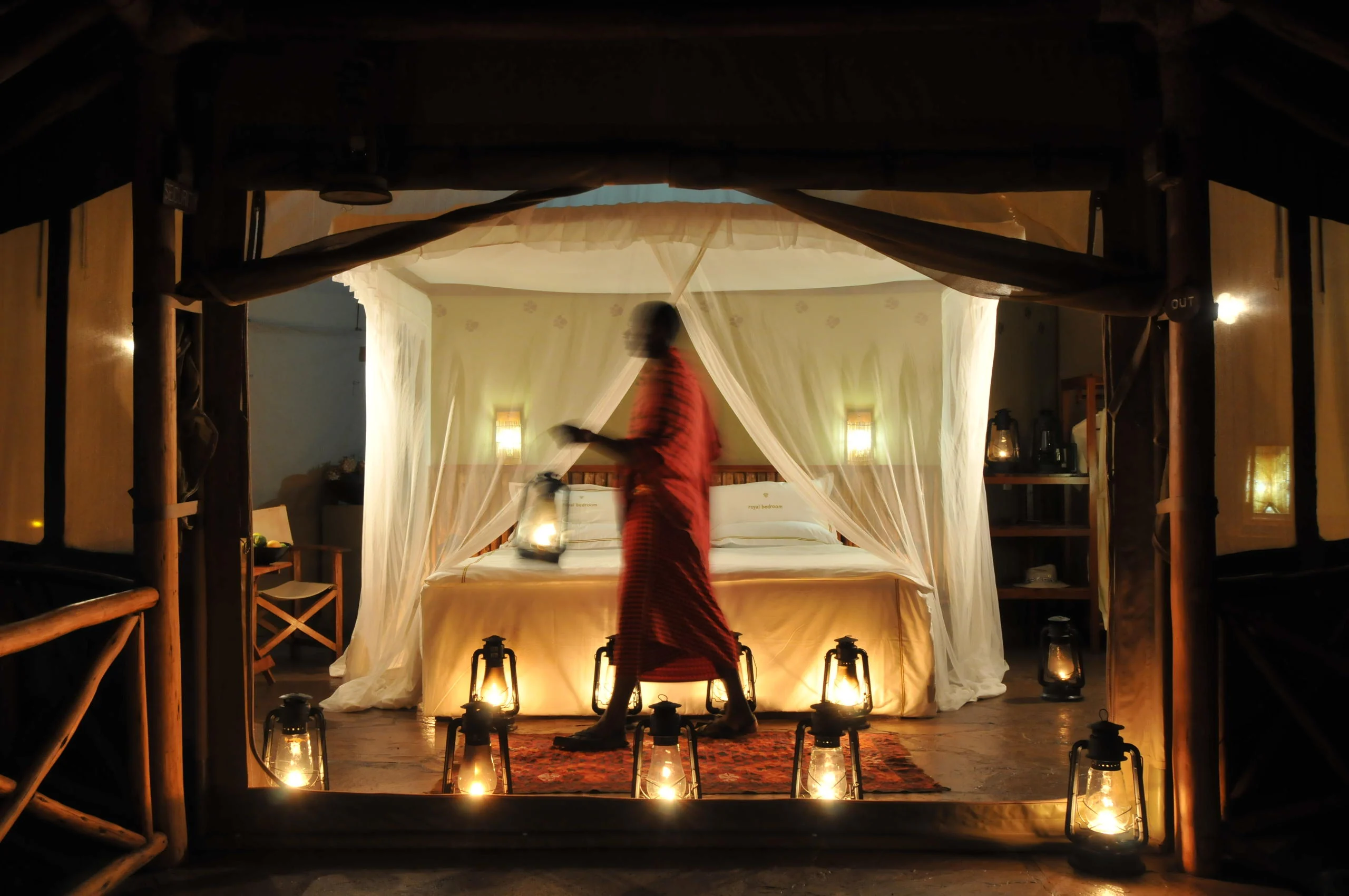 A tent bedroom lit by lanterns in the evening
