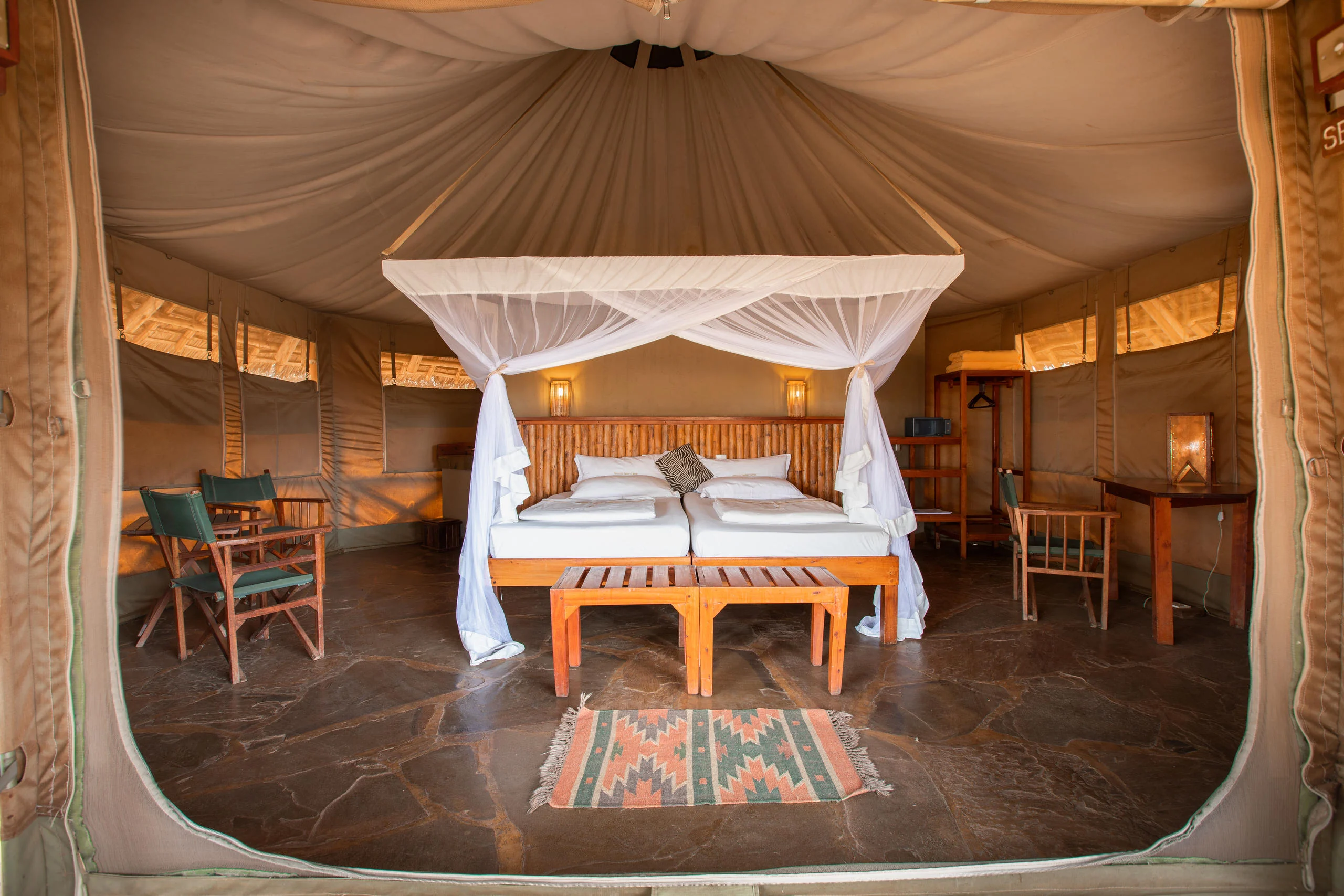 A tent bedroom with a draped bed and a patterned rug